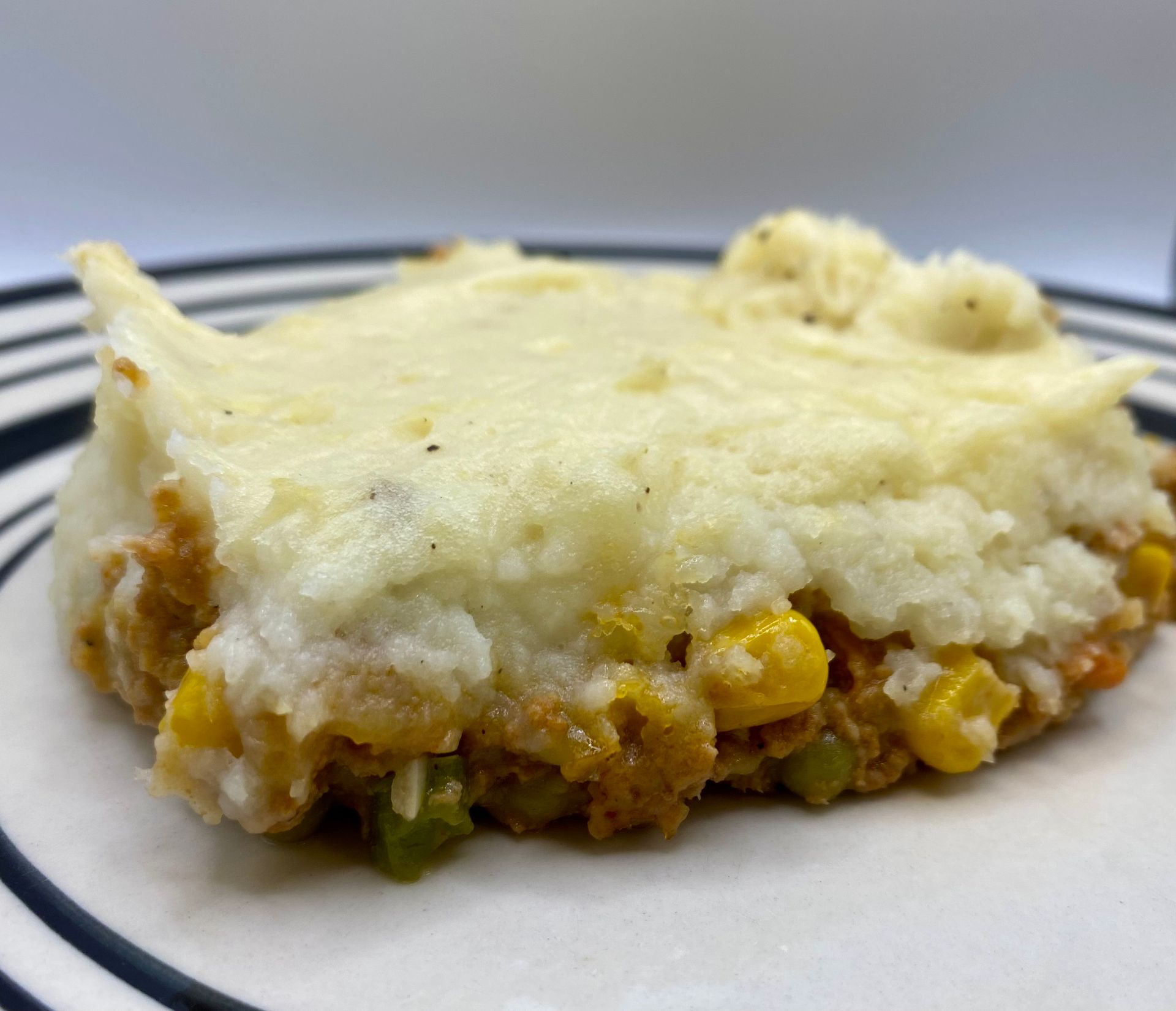 Shepherd's pie on a plate, featuring a layer of mashed potatoes over a meat and vegetable filling.