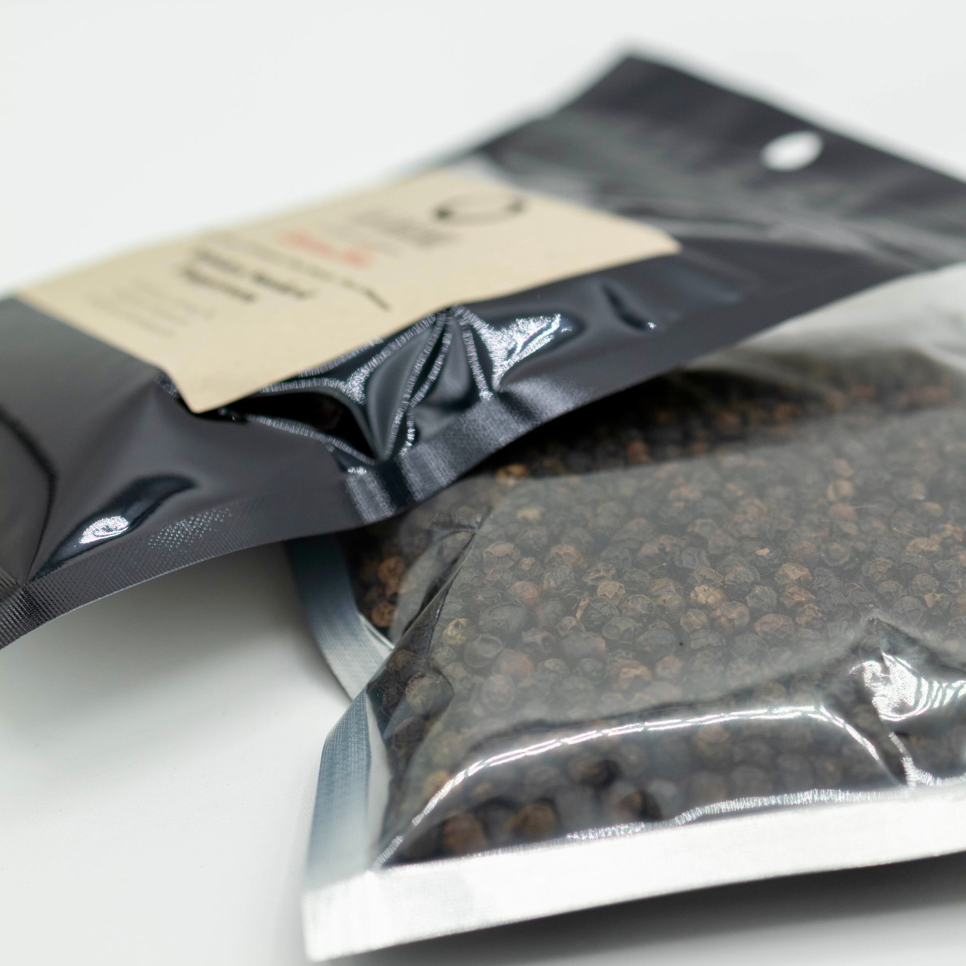 A bag of whiskey smoked peppercorns next to a bottle of whiskey