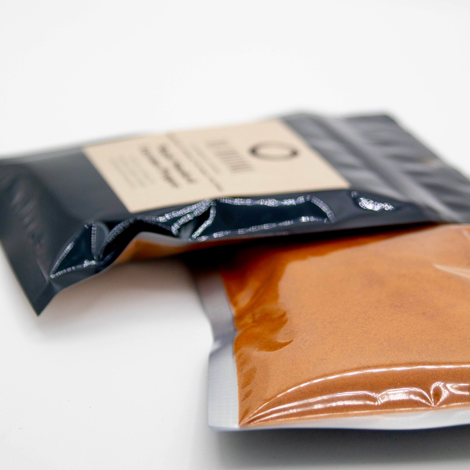 A bag of maple smoked espresso pepper next to some peppers