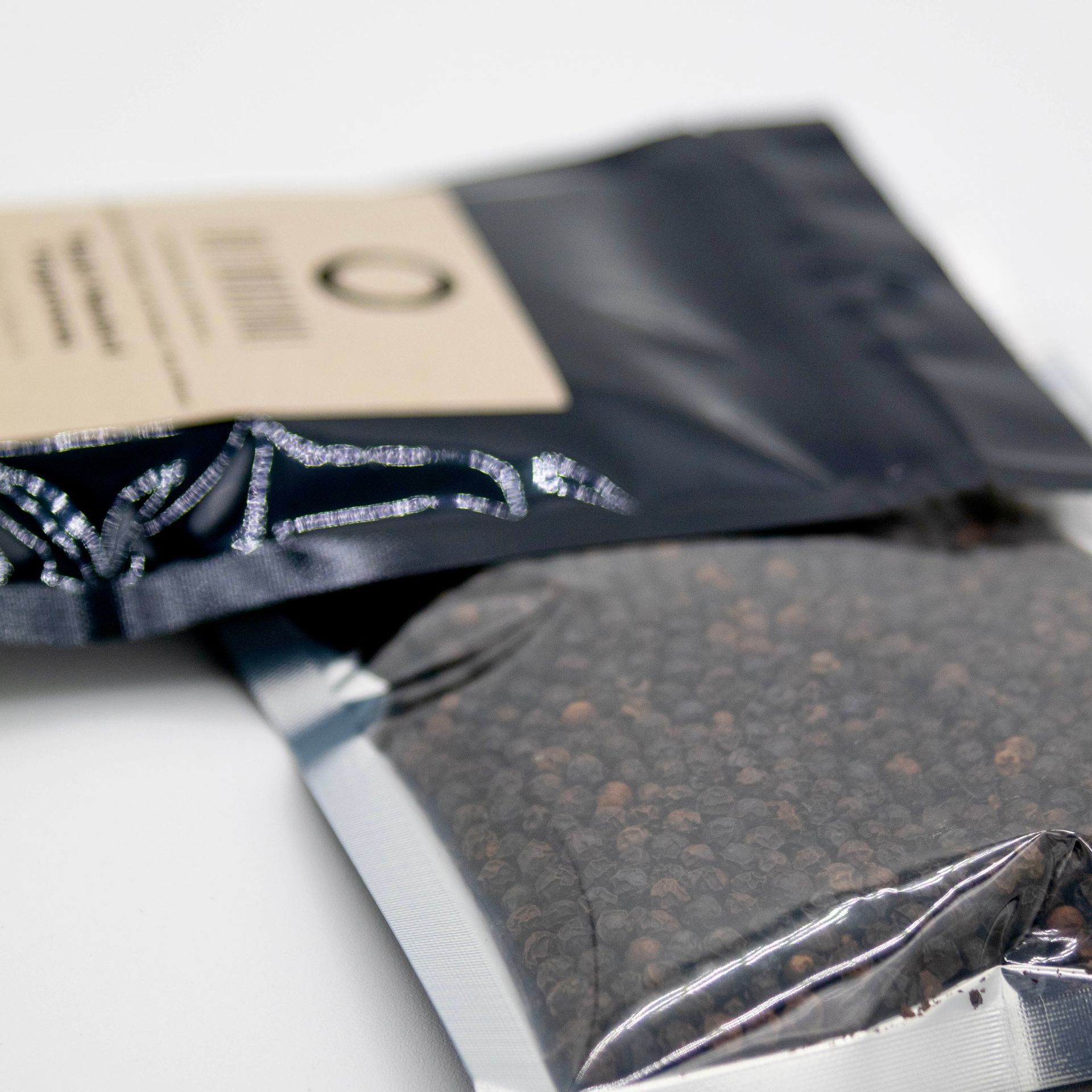 A bag of maple smoked peppercorns next to a glass of wood chips