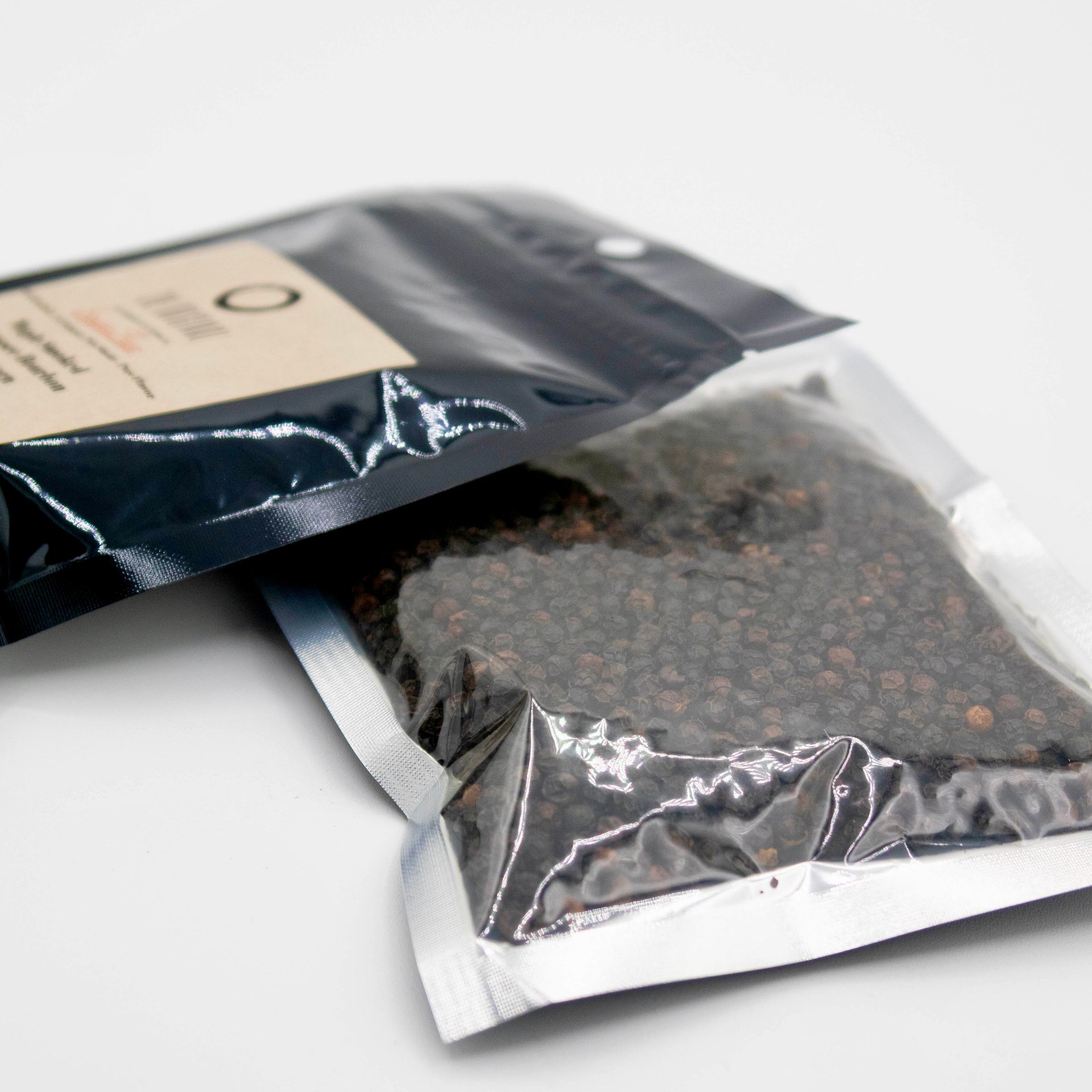 A bag of peppercorns sits next to a bottle