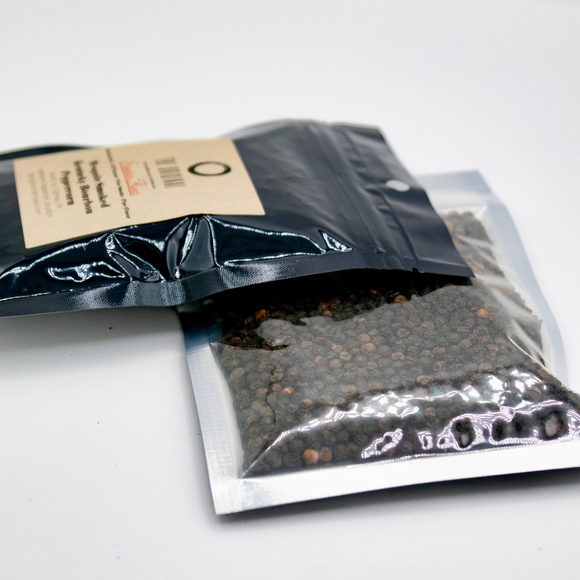 A bag of pepper next to a bottle and a glass