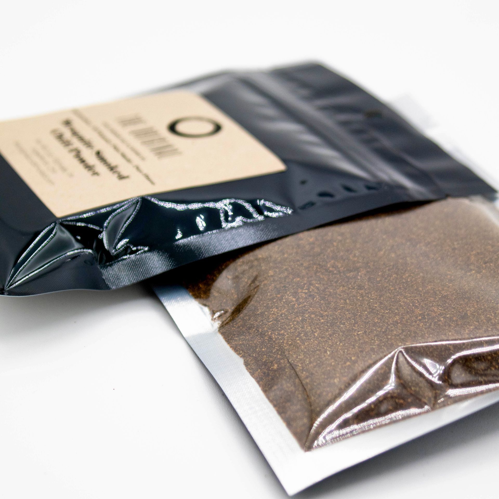 A bag of mosquito smoked chili powder next to a glass of smoked chili powder