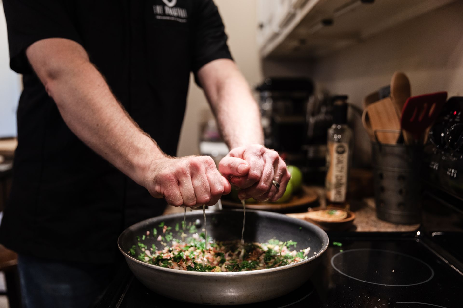 A man is cooking food in a frying pan on a stove.