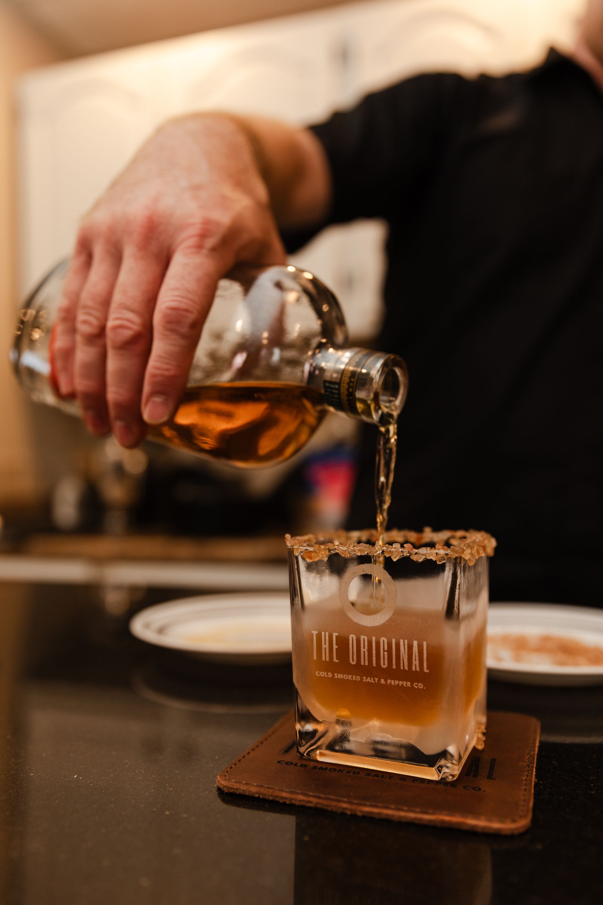 A man is pouring a drink from a bottle into a glass.
