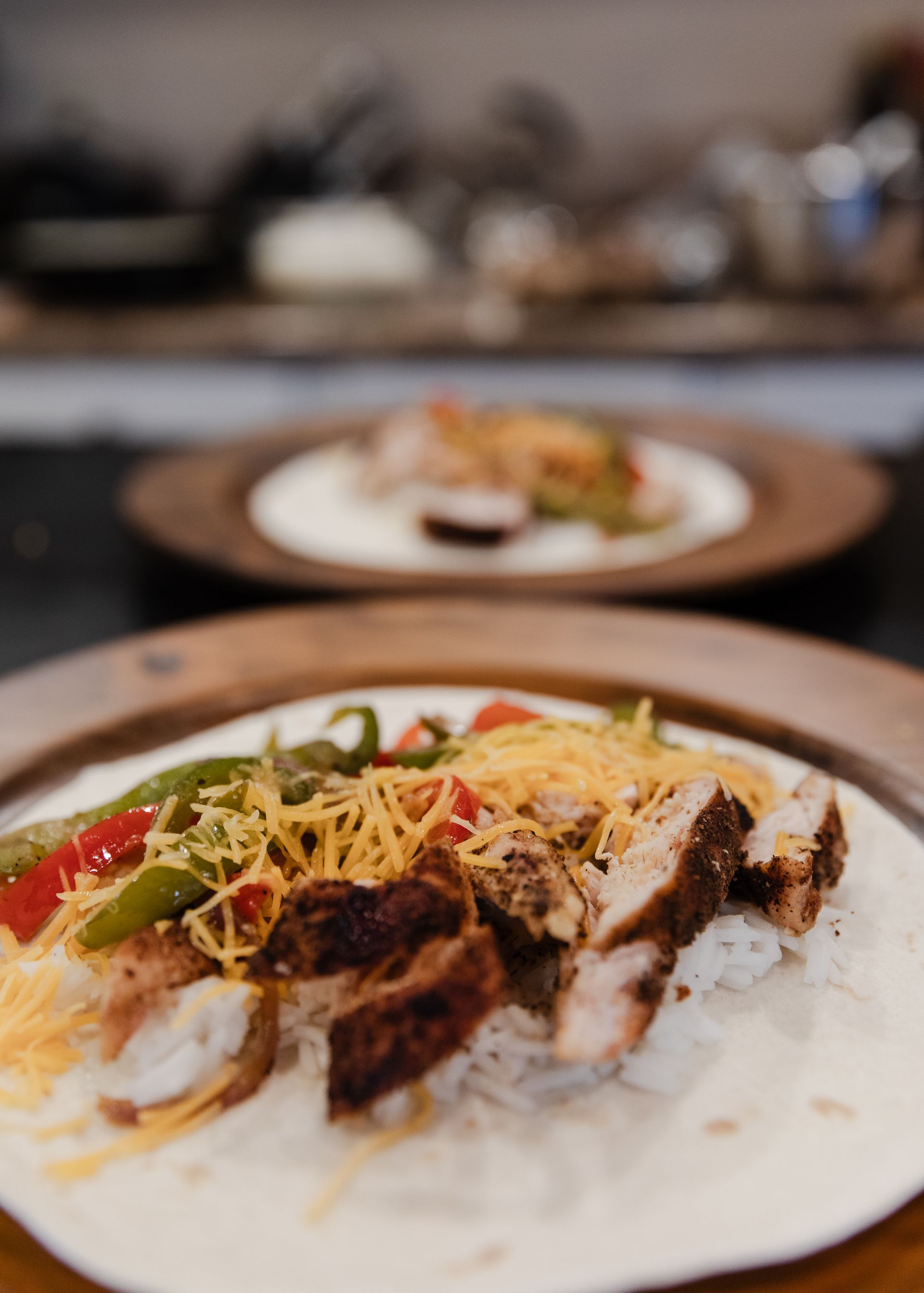 A close up of a tortilla with meat and vegetables on a wooden tray.