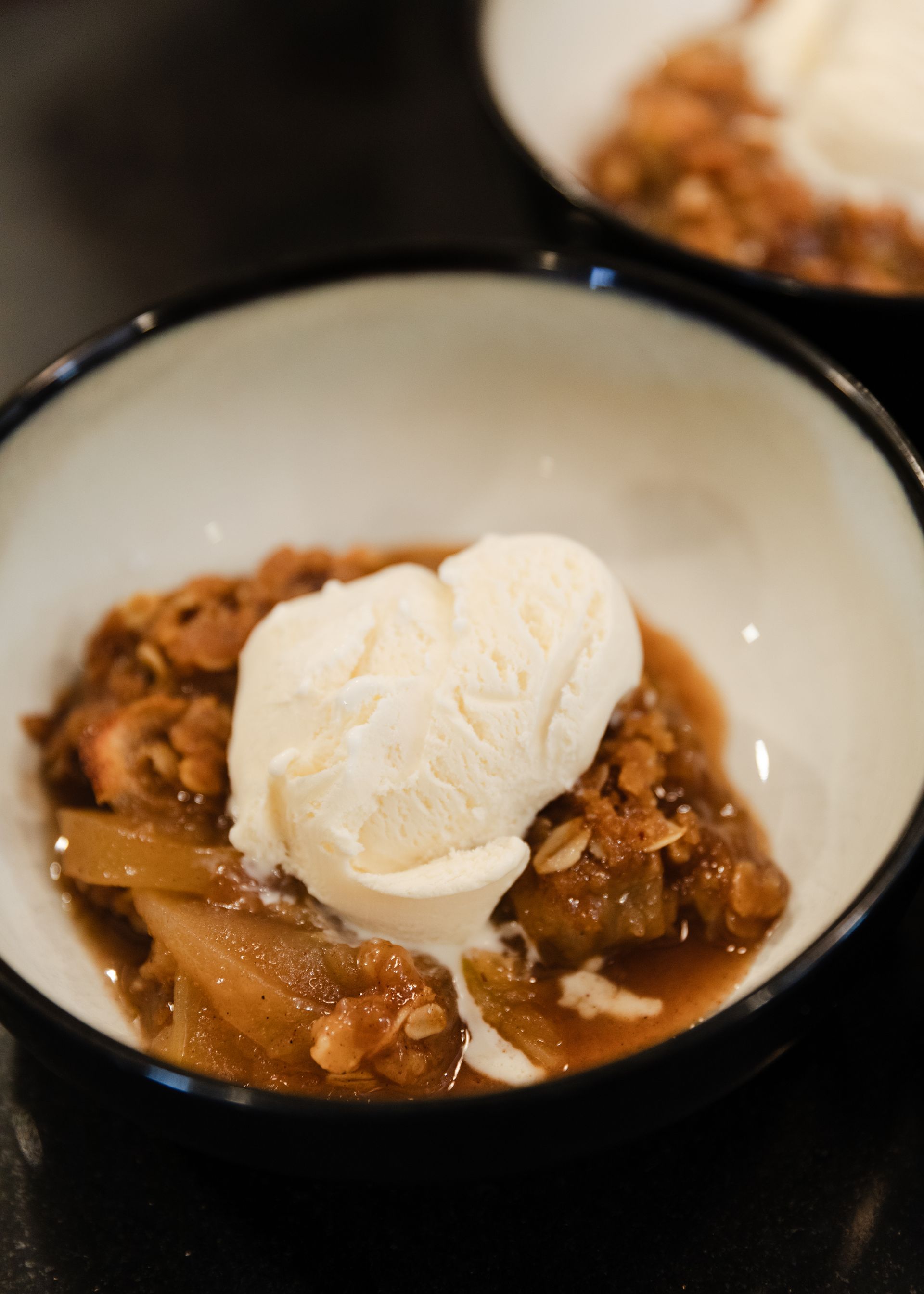 A bowl of apple crisp with ice cream on top