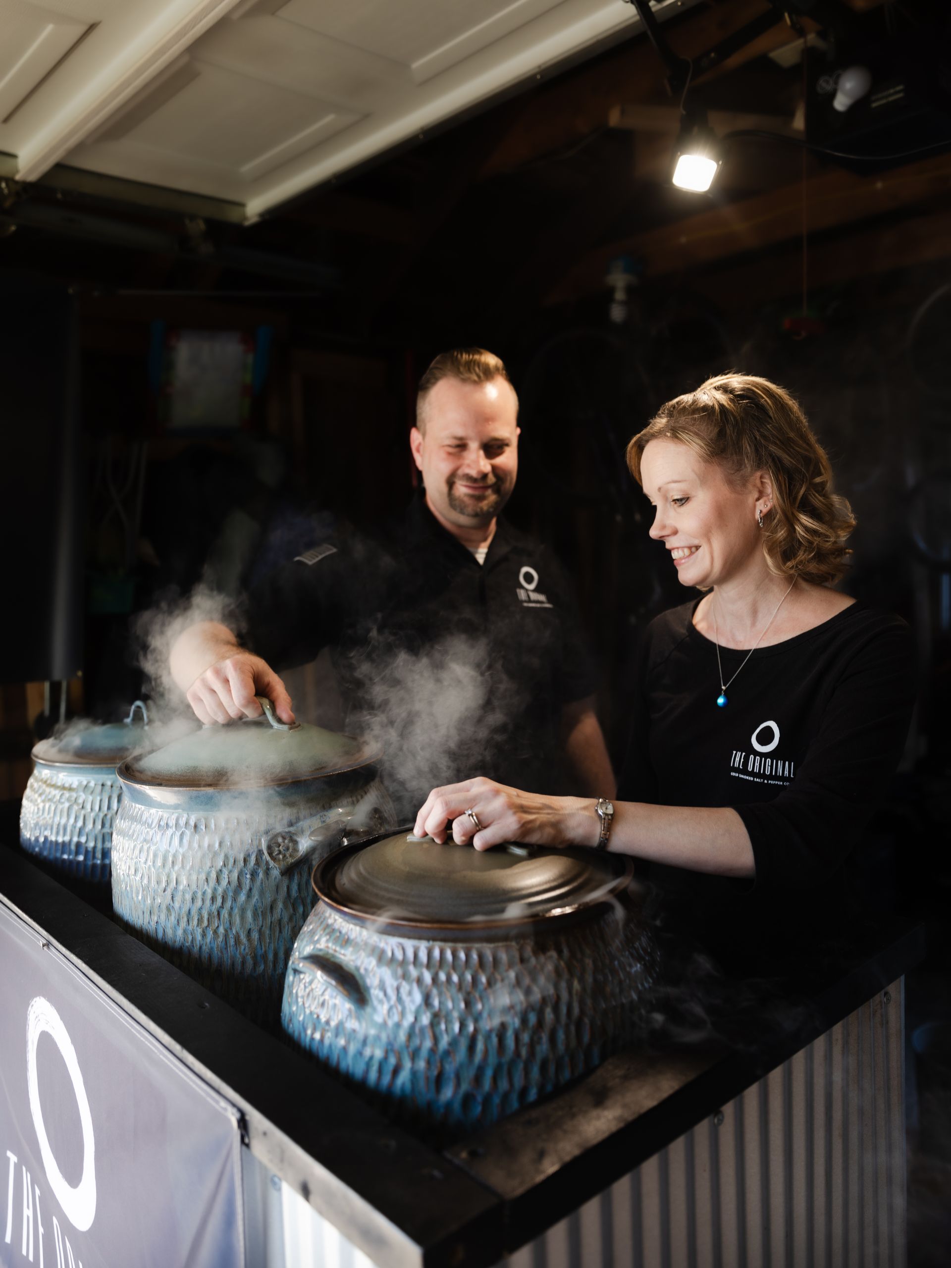 A man and a woman are cooking in pots on a counter.