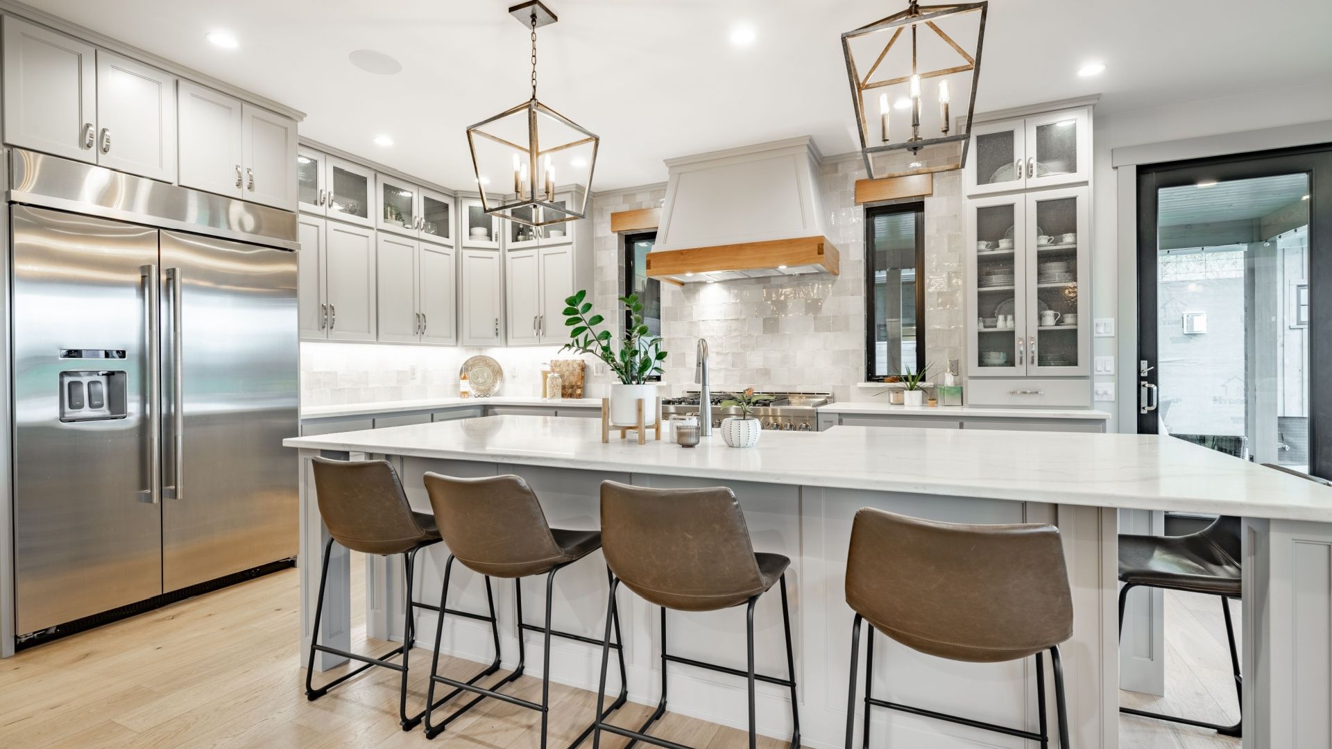 A kitchen with white cabinets , stainless steel appliances , a large island and stools.