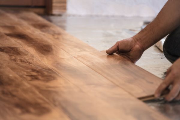 A person is installing a wooden floor in a room.