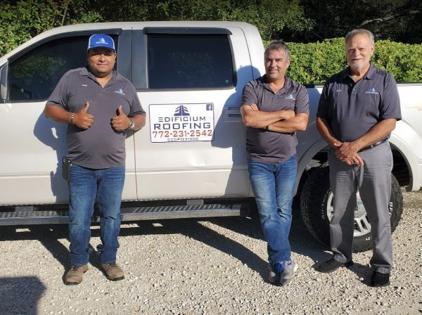 Three men standing in front of a roofing truck