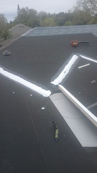 A black roof with white tape on it is being repaired.