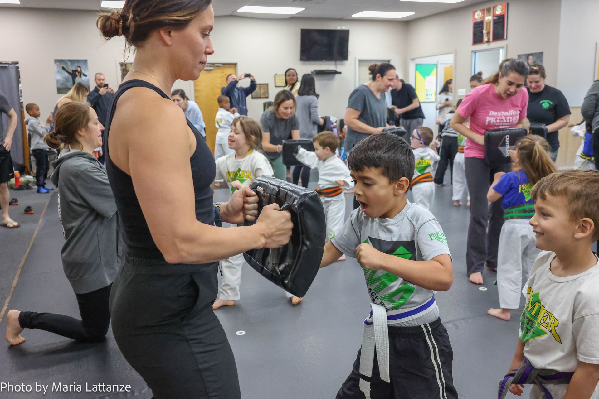 A woman is teaching a group of children martial arts in a gym.