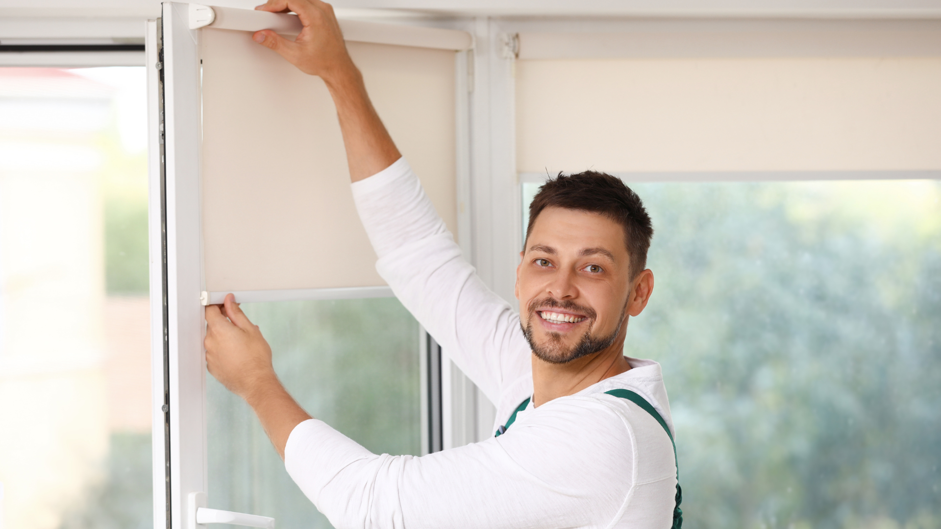 A man is installing blinds on a window.
