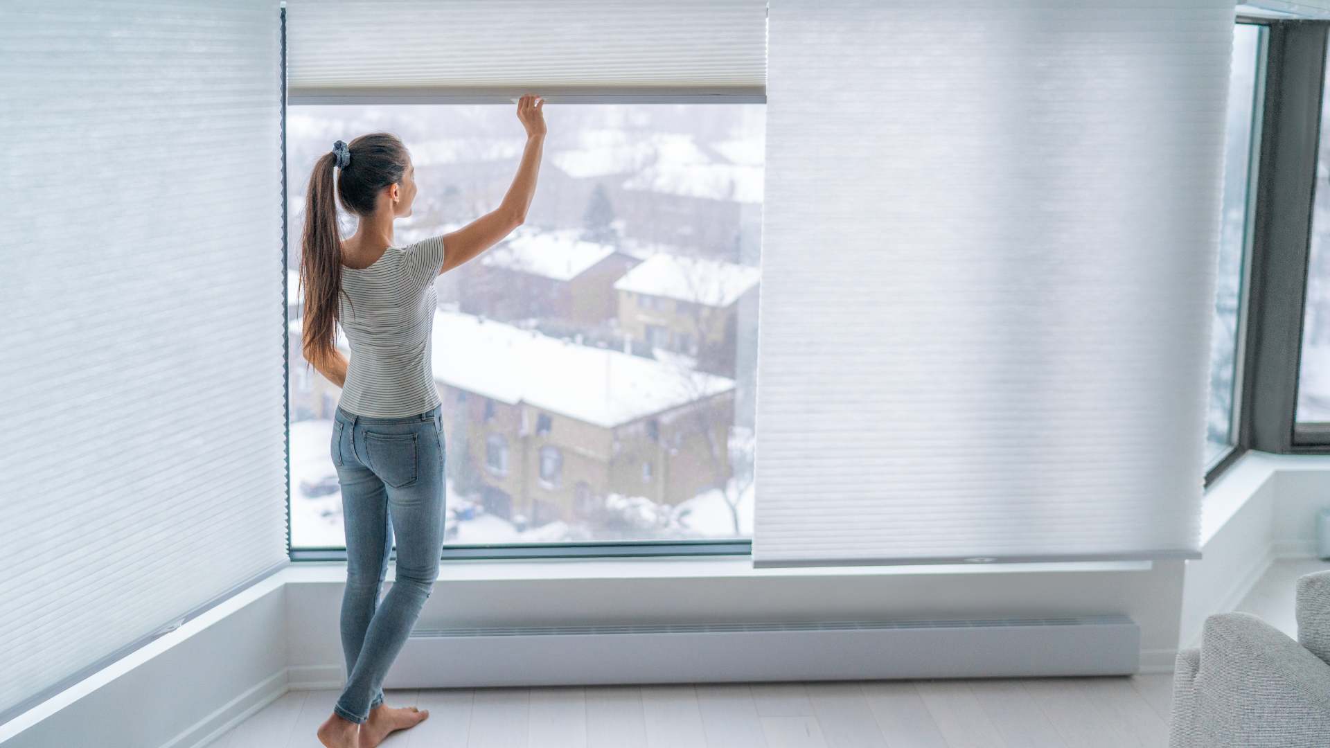 A woman is standing in front of a window looking out.