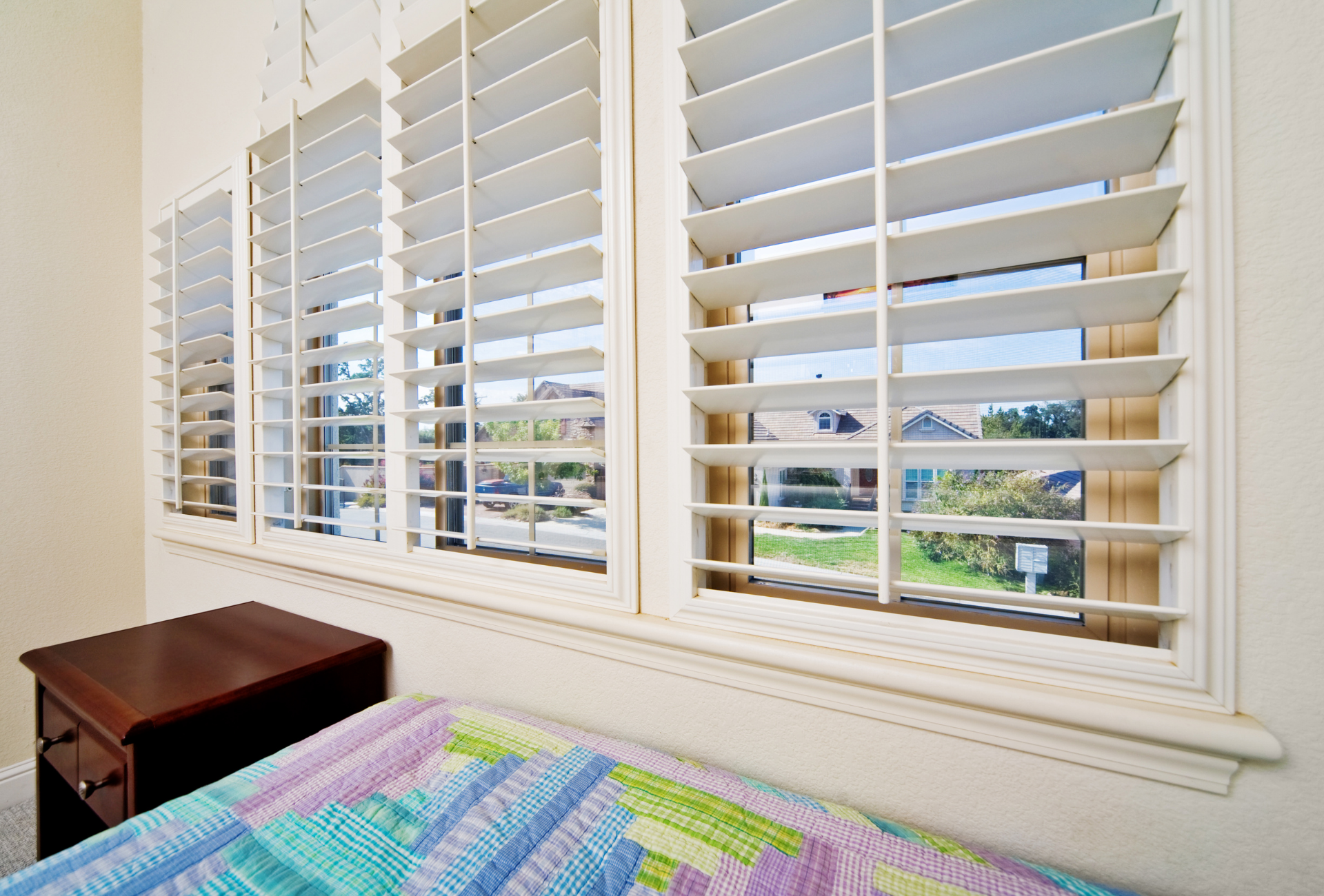 A bedroom with a bed and shutters on the windows
