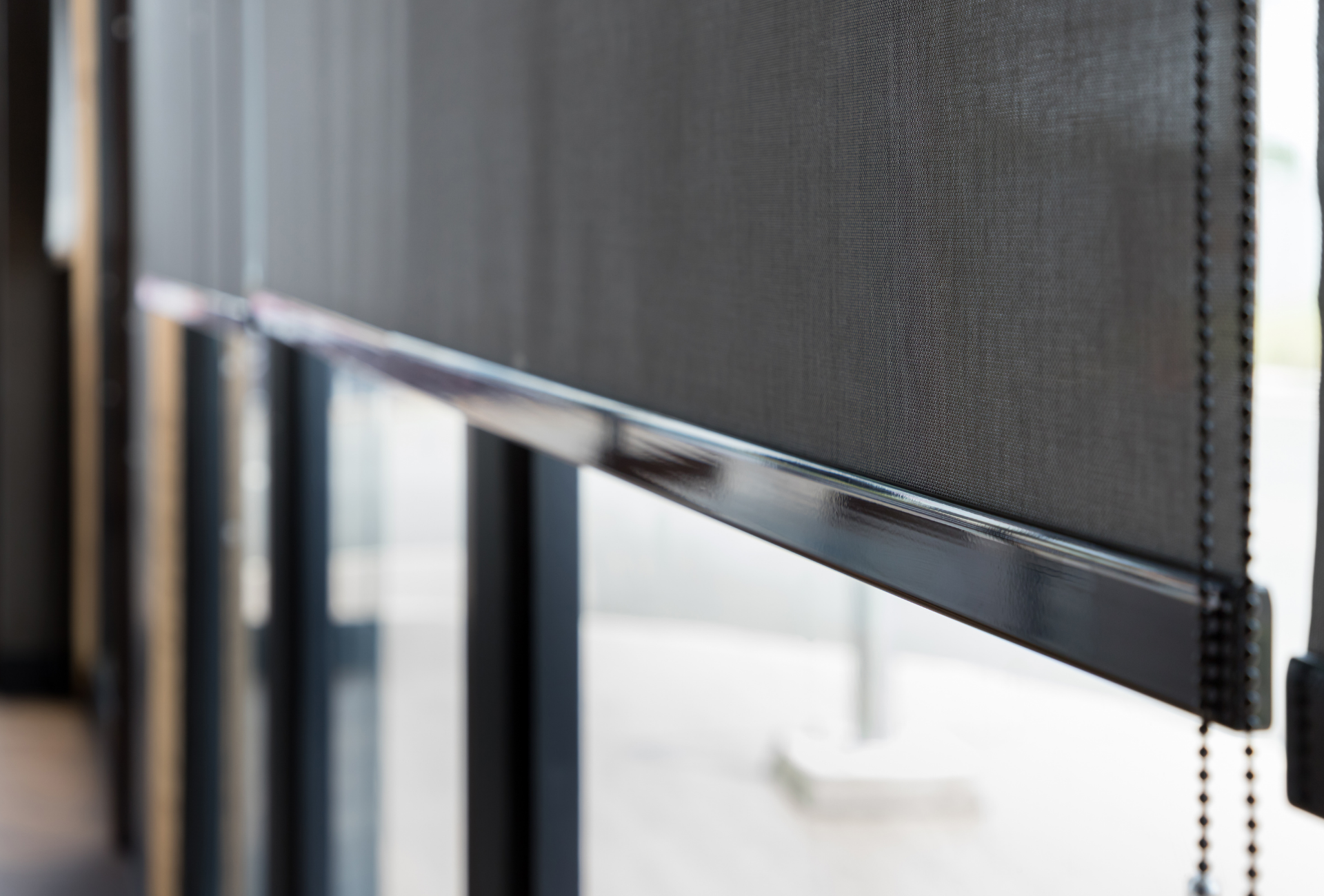 A close up of a black roller blind on a window.
