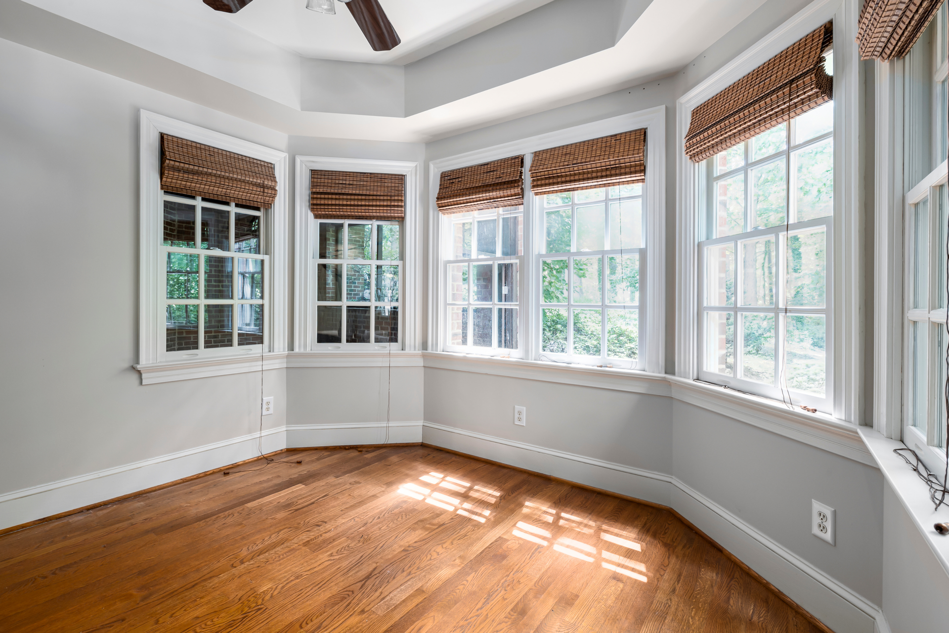An empty room with hardwood floors and lots of windows.