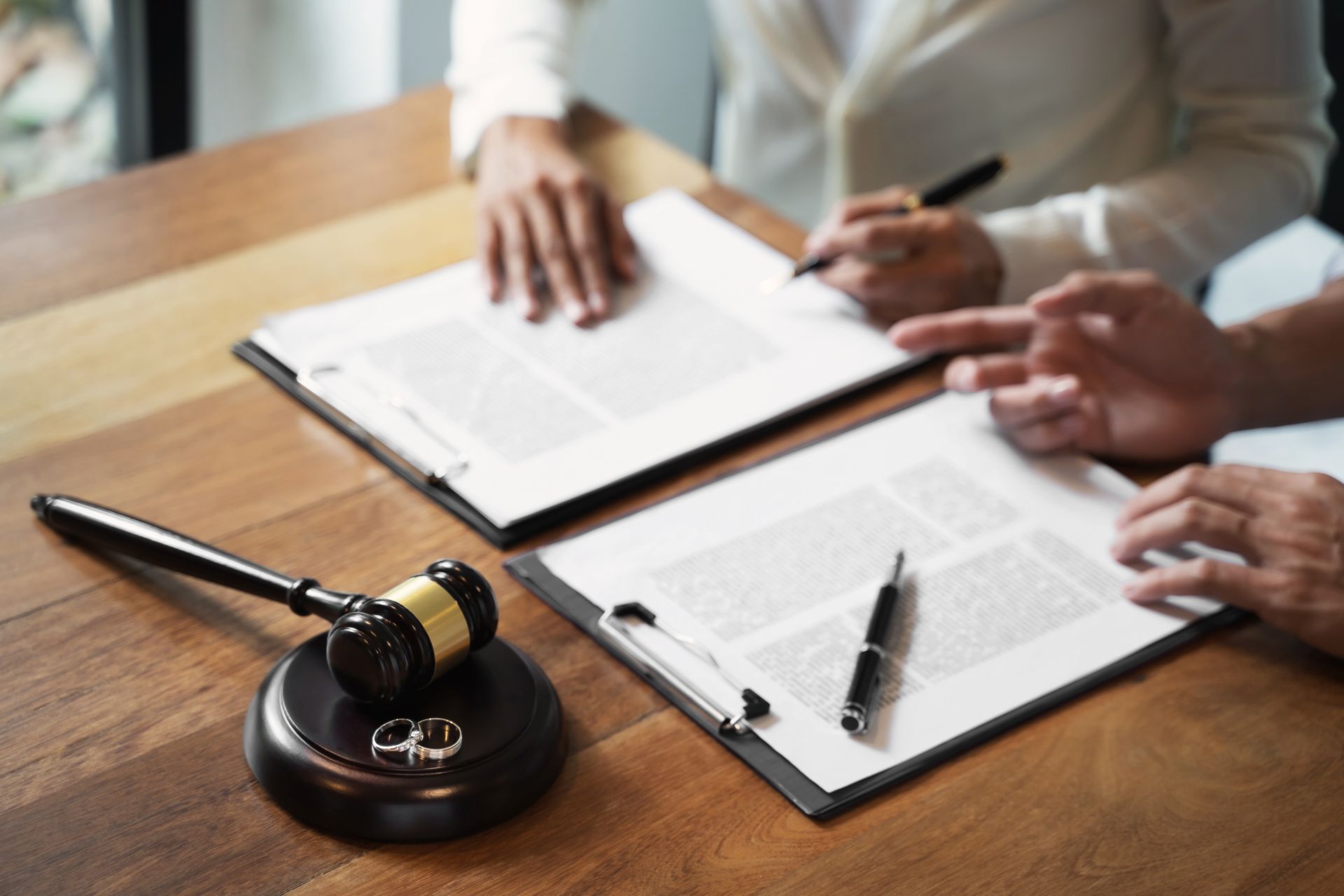 Divorce paperwork with gavel and wedding rings on desk.