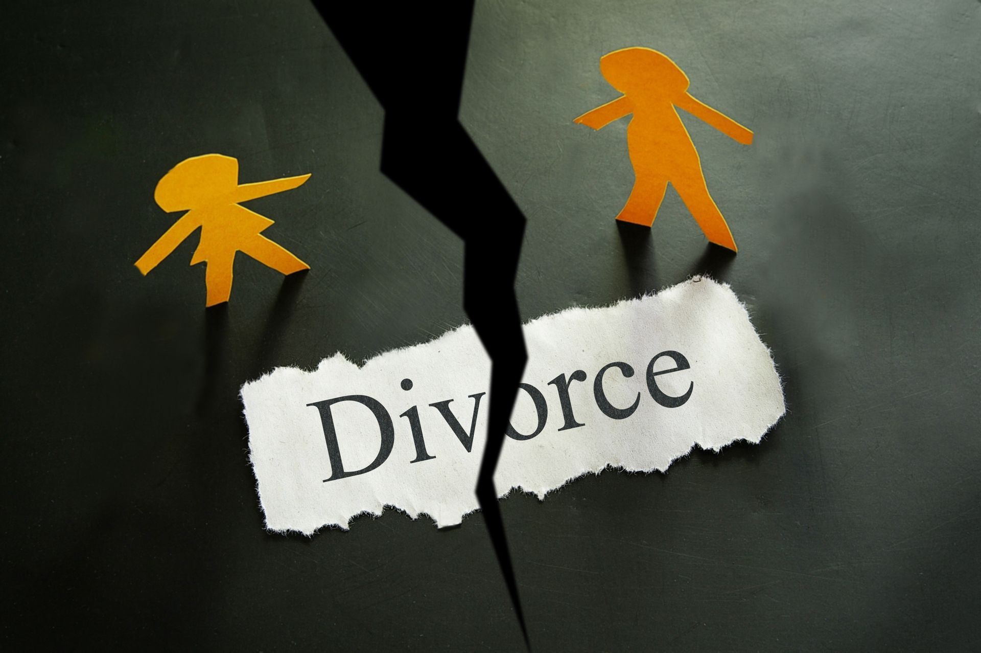 Torn paper reading “Divorce” with two cutout figures separated by a jagged black crack. Torn paper reading “Divorce” with two cutout figures separated by a jagged black crack.