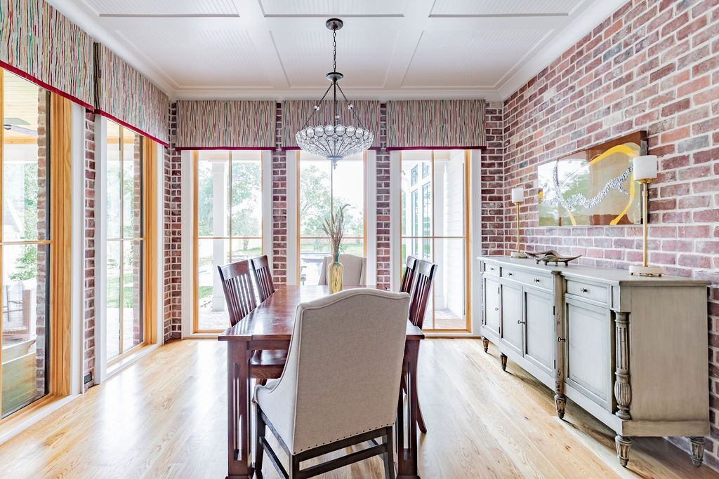 A dining room with a table and chairs and a brick wall.