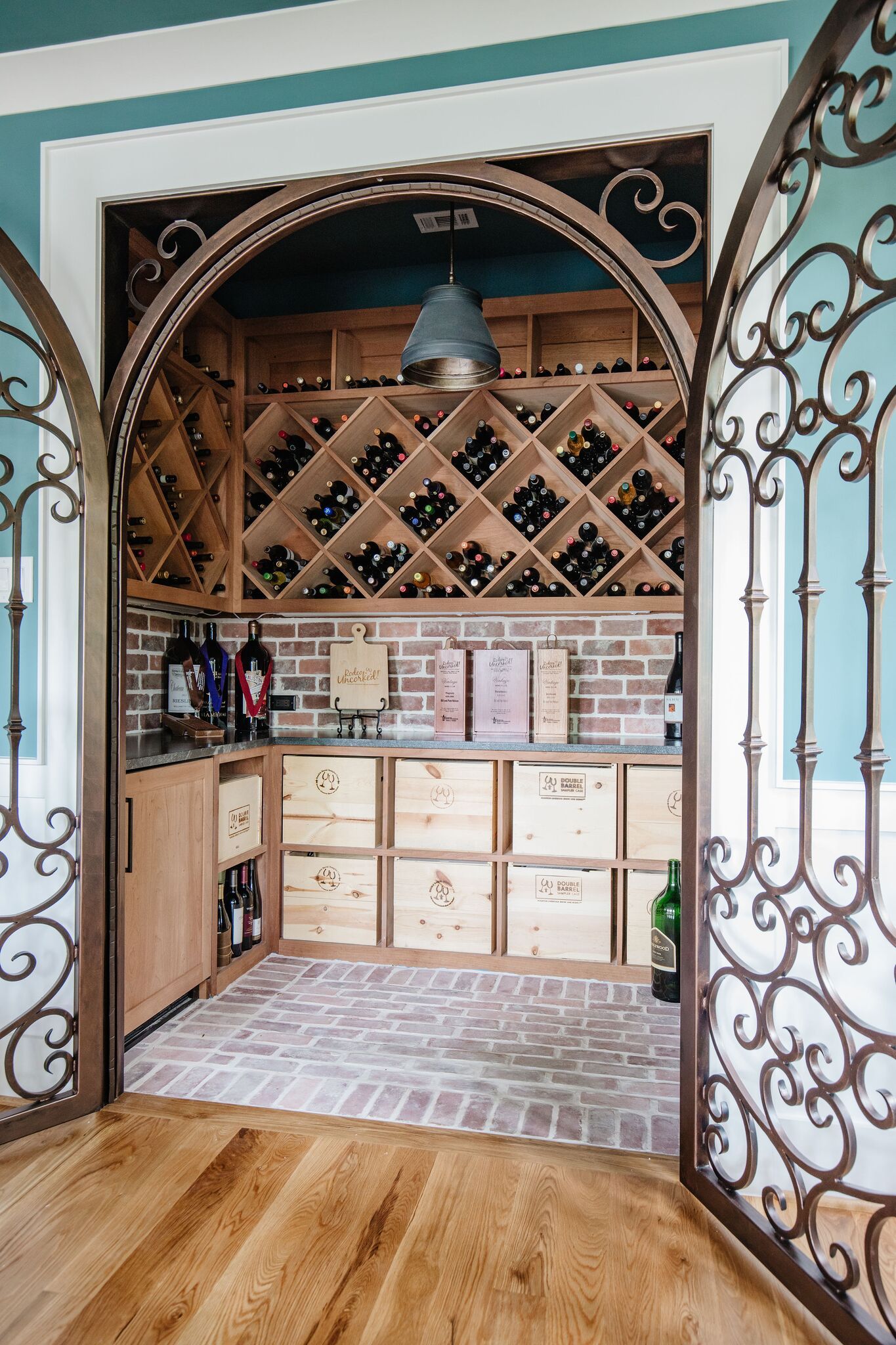 A wine cellar with a wrought iron gate and wooden shelves filled with wine bottles.