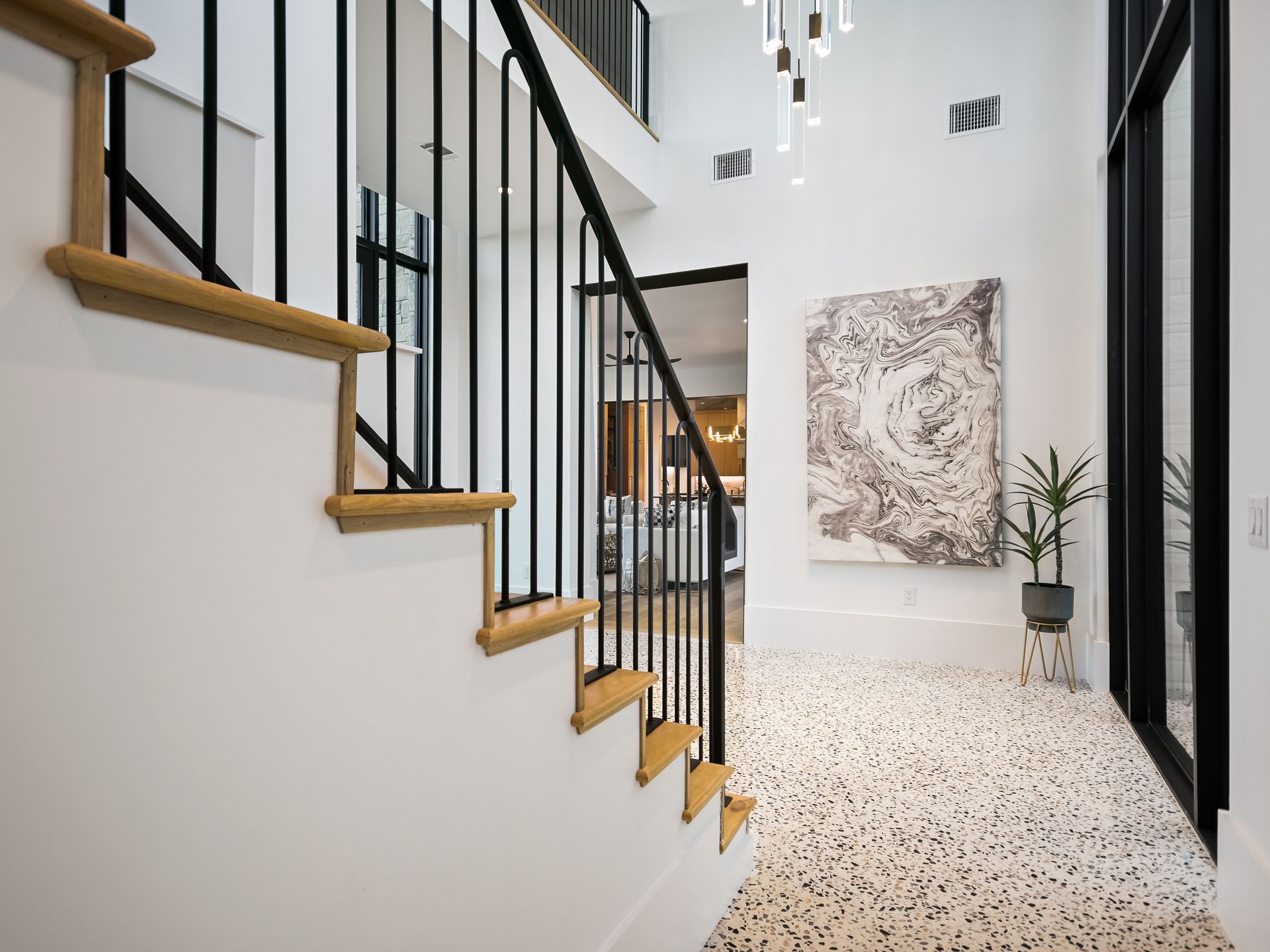 A staircase in a hallway with a black railing and a painting on the wall.