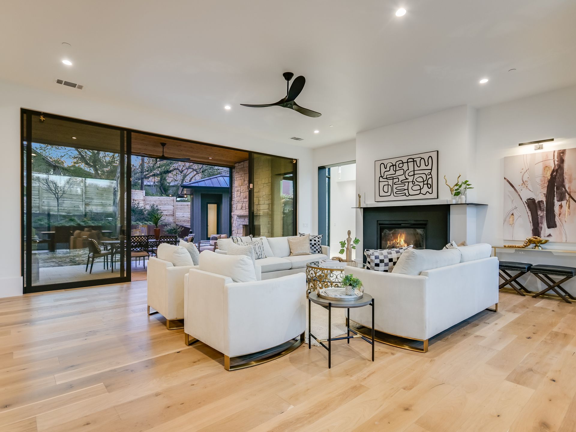 A living room with white furniture , a fireplace and a ceiling fan.