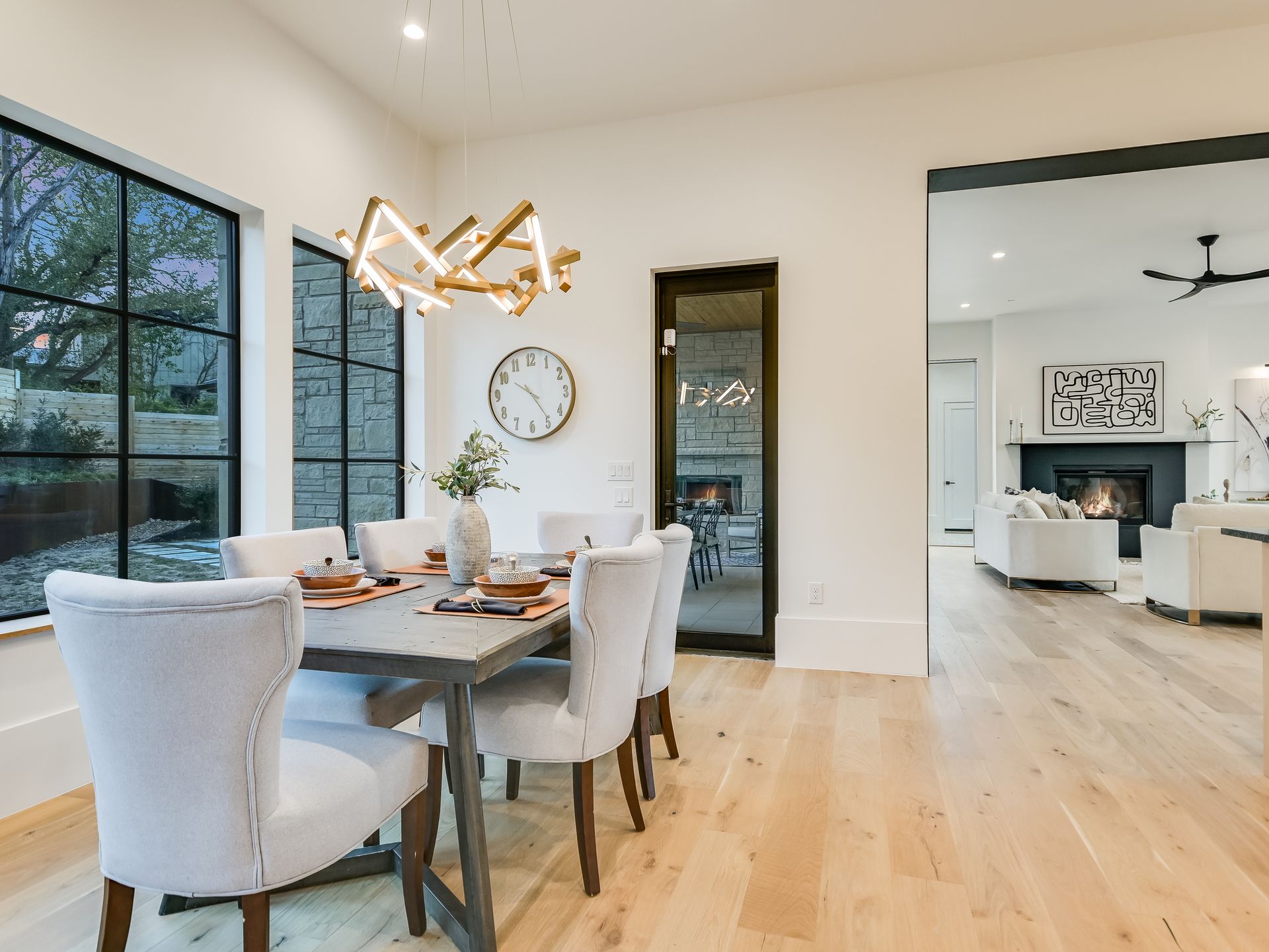 A dining room with a table and chairs and a clock on the wall.