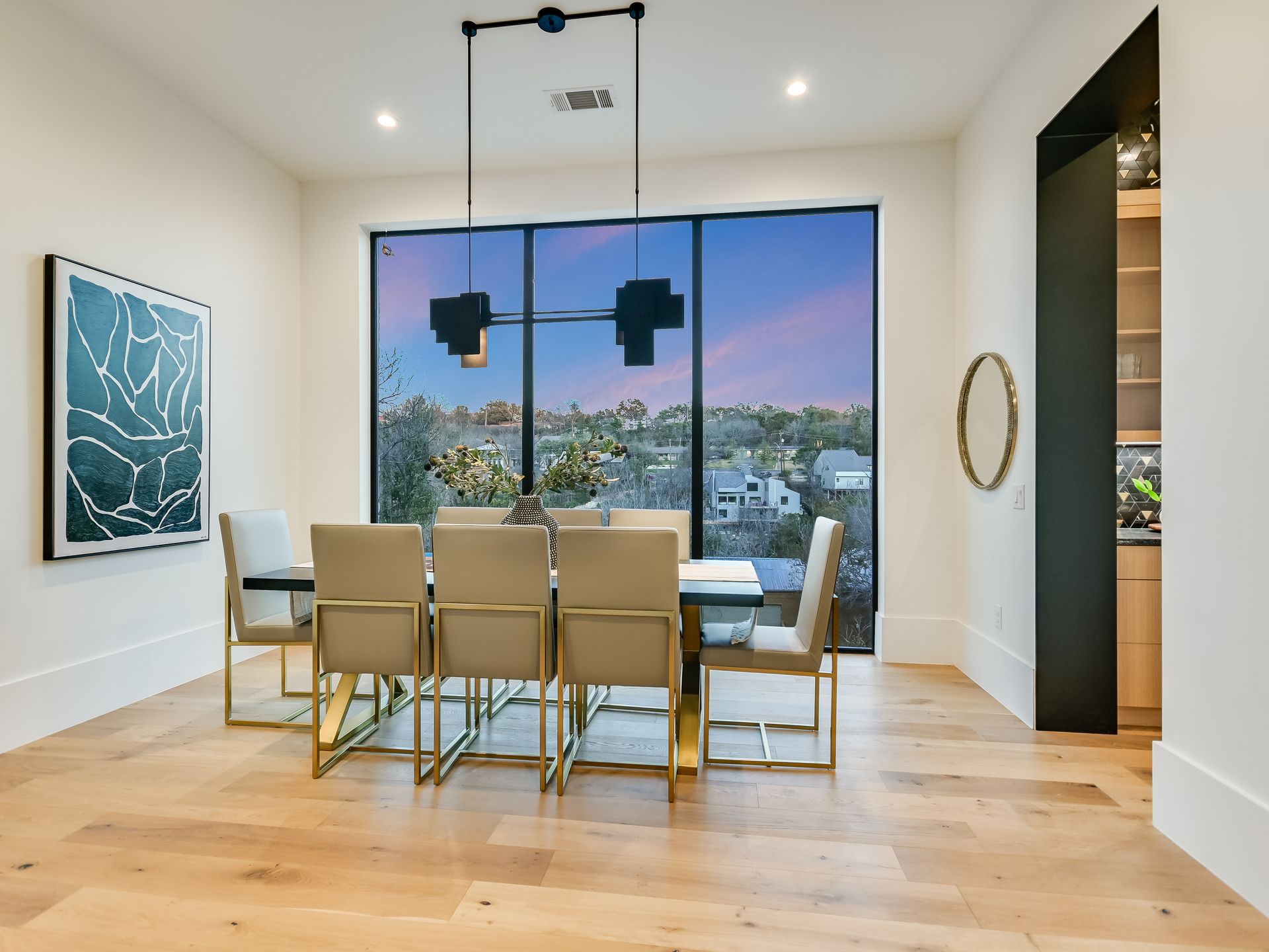 A dining room with a table and chairs and a large window