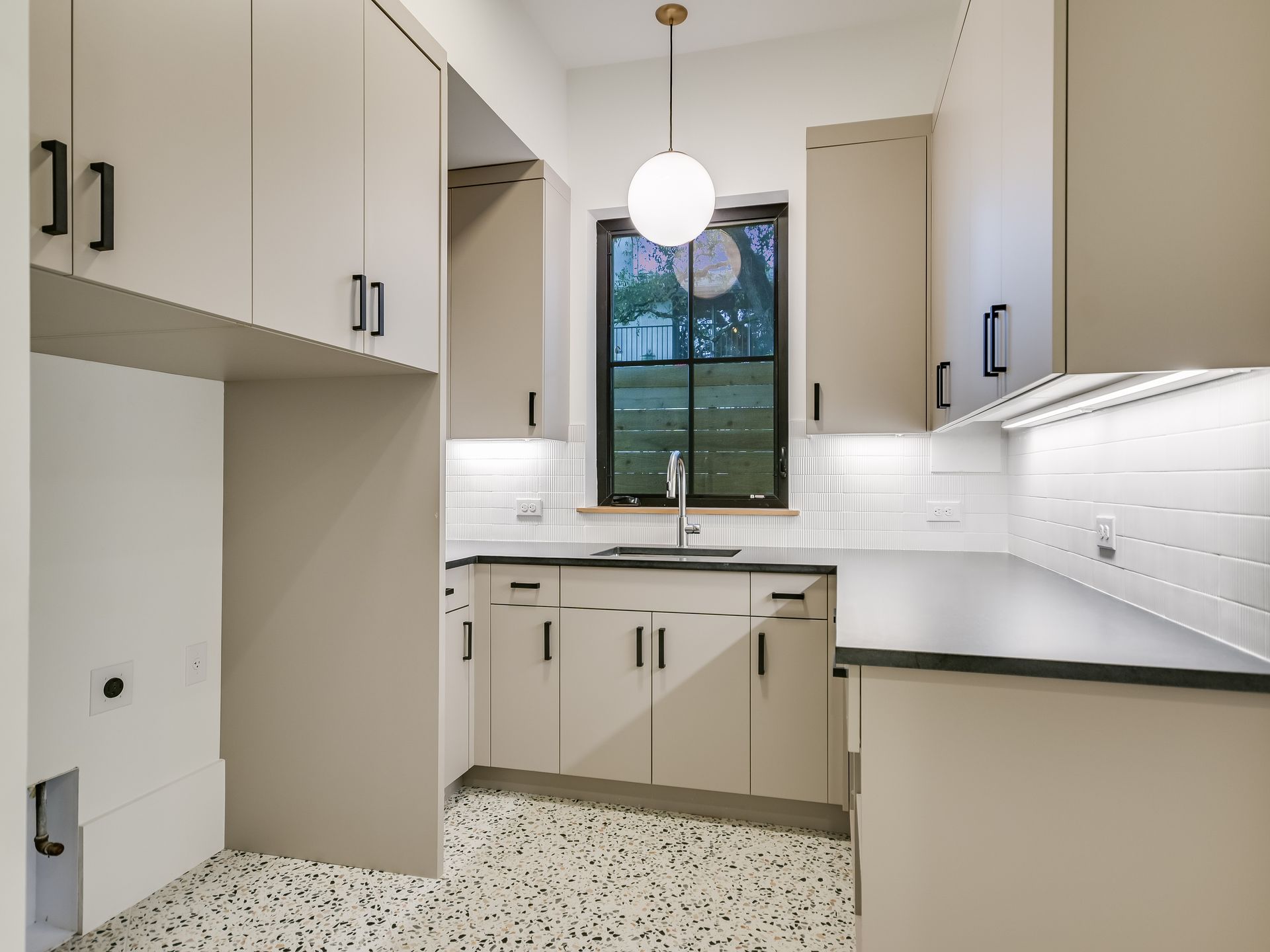 A kitchen with a sink , cabinets and a window.