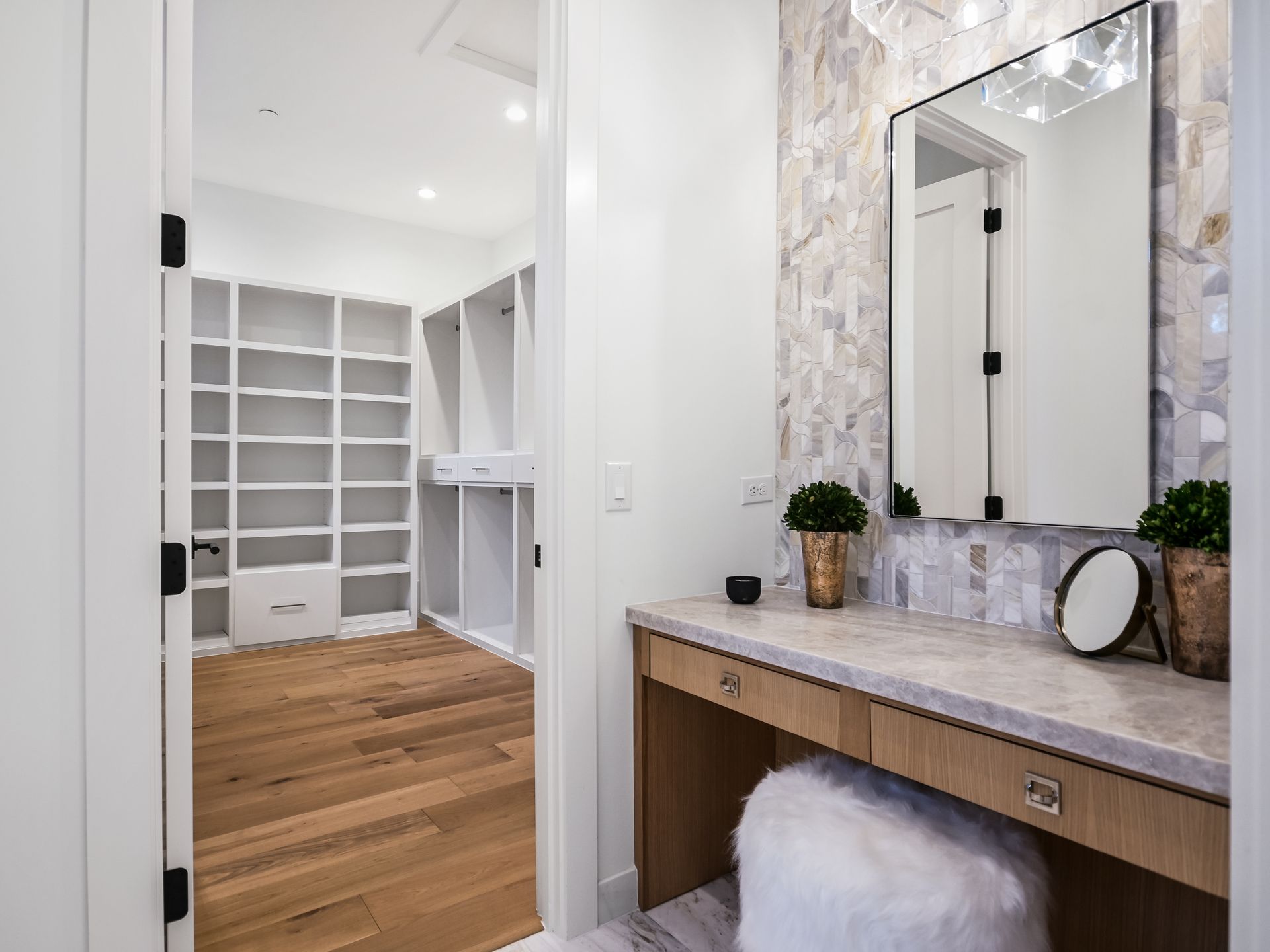 A bathroom with a vanity , mirror , and walk in closet.