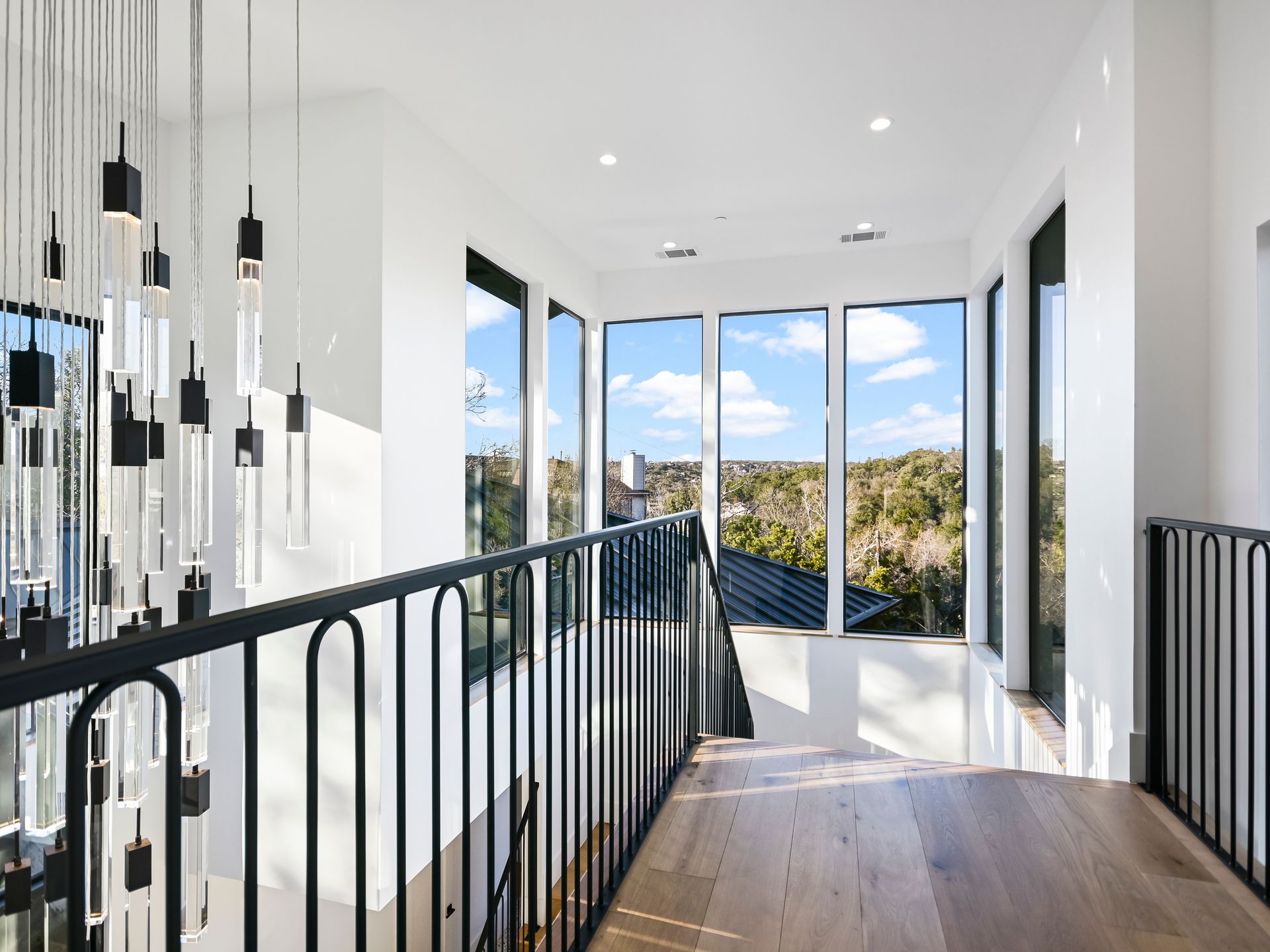 A hallway with a railing and lots of windows in a house.