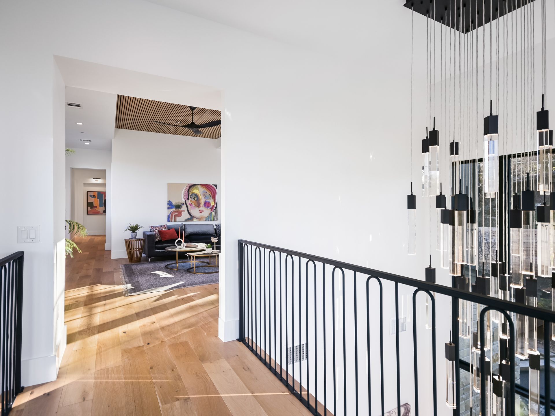 A hallway with a black railing leading to a living room.