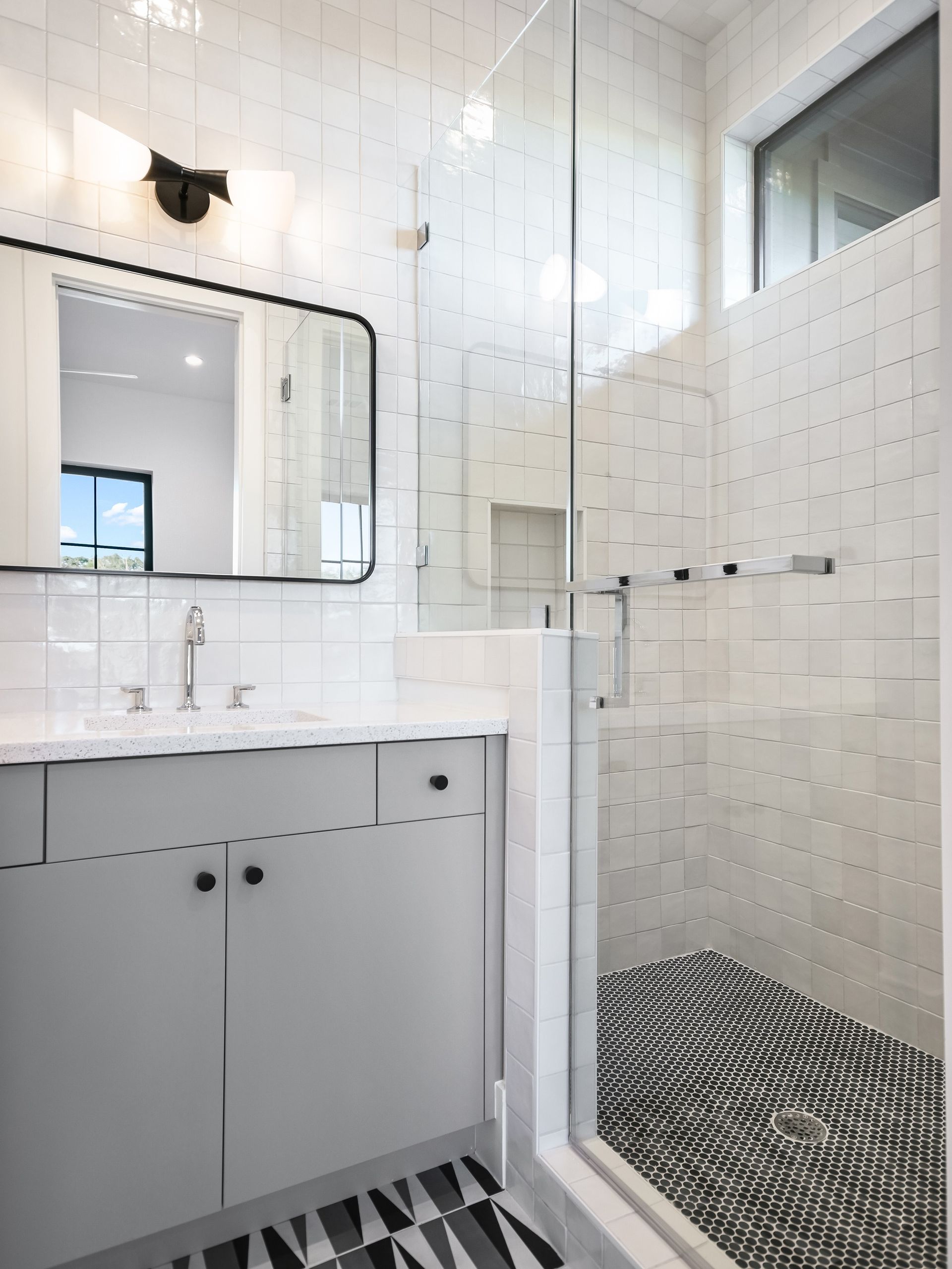A bathroom with a walk in shower and a sink