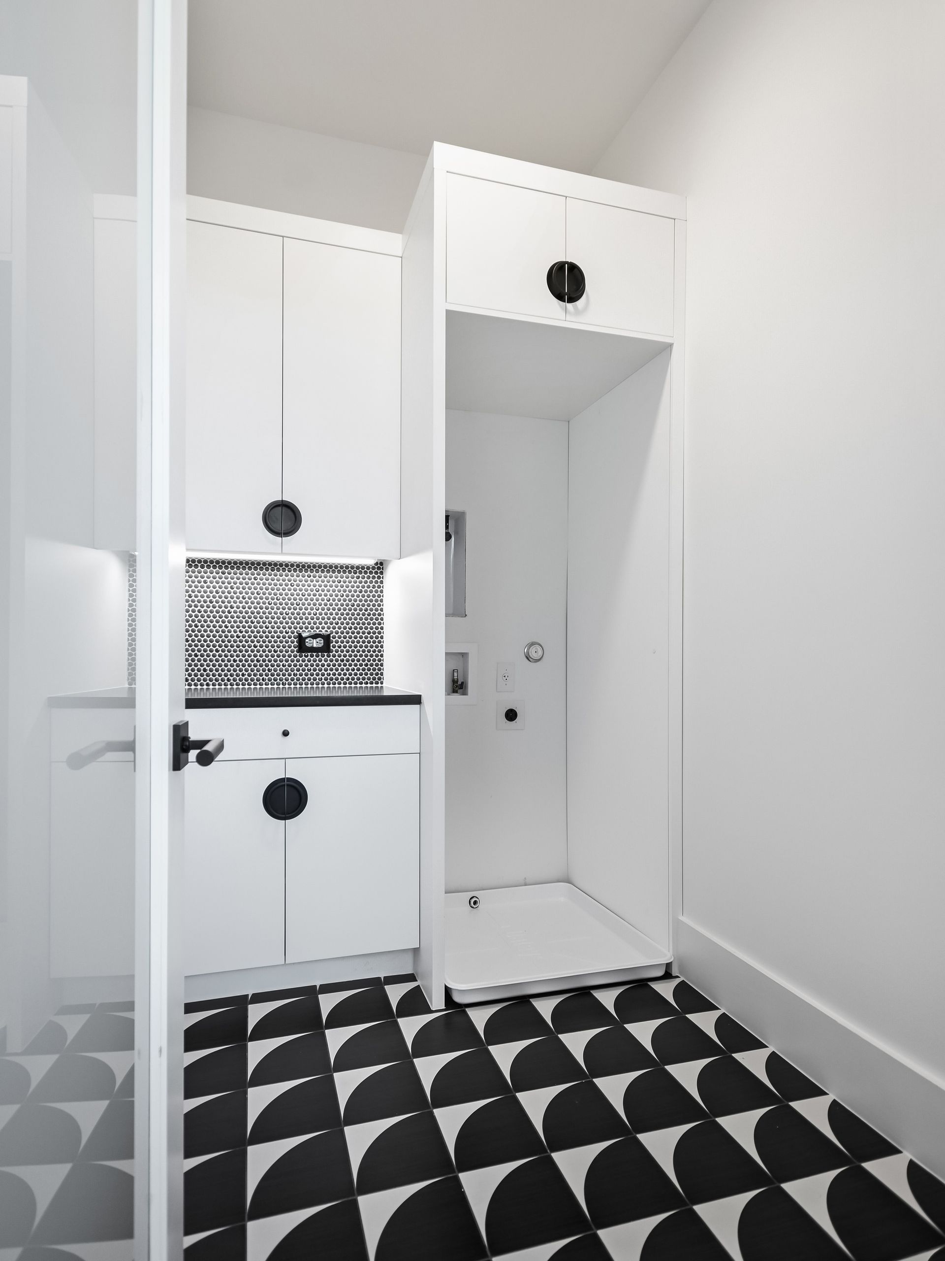 A kitchen with black and white tiles and white cabinets