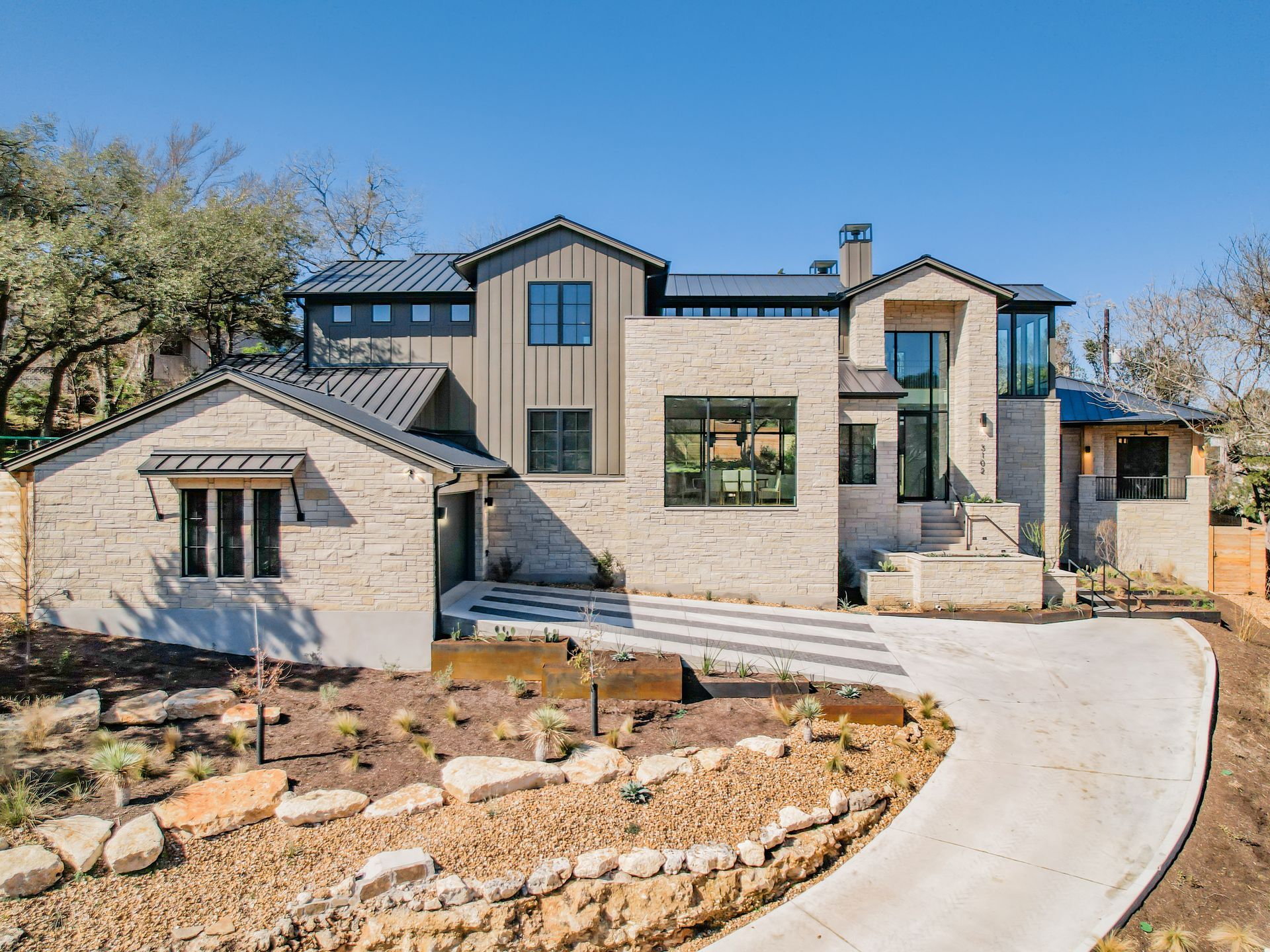 A large house with a lot of windows and a driveway leading to it.