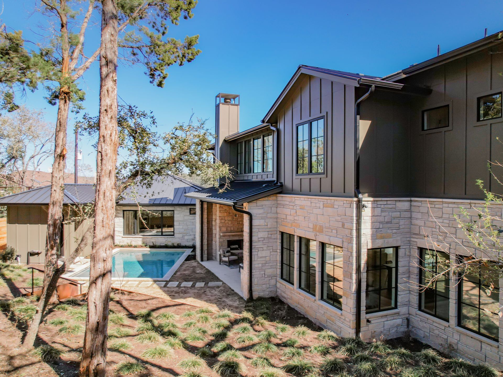 A large house with a swimming pool in the backyard surrounded by trees.