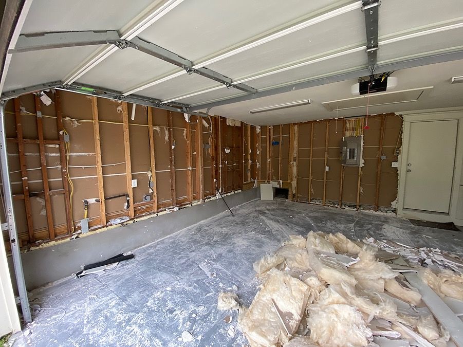 A garage with a garage door open and a lot of insulation on the floor.