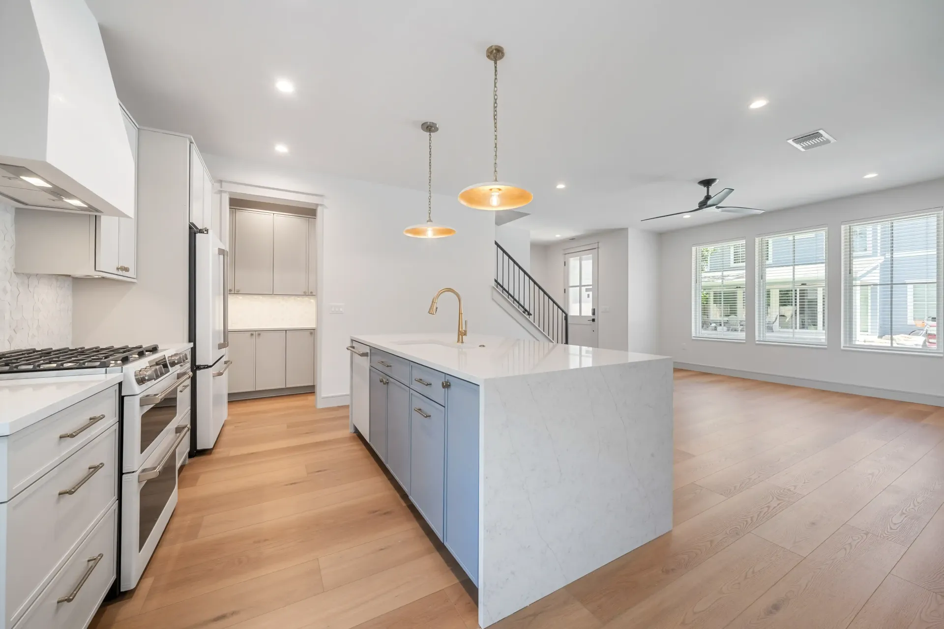 Modern kitchen with white countertops, blue island, and light wood floors.