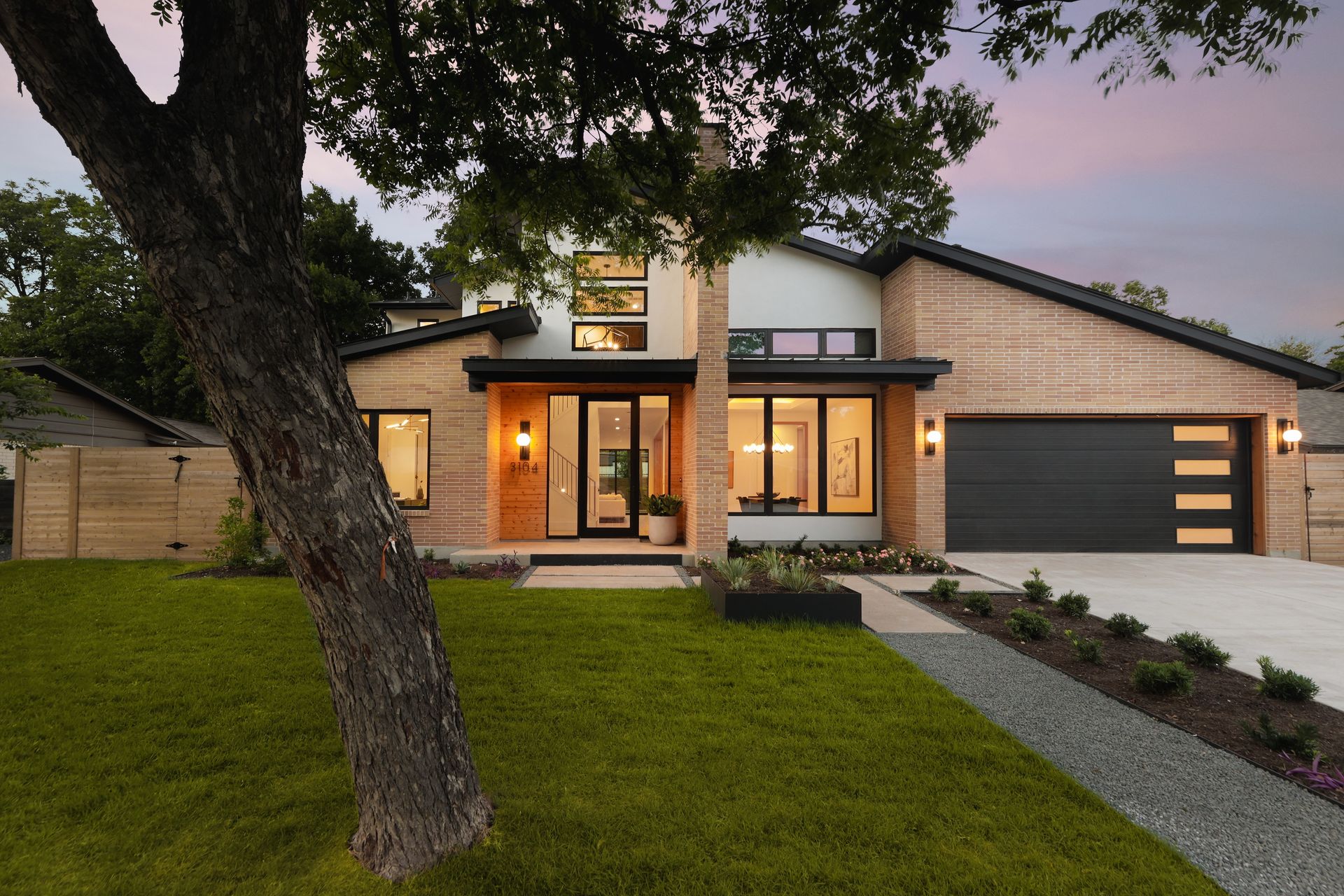 Modern two-story house with wood siding, black garage door, and green lawn.