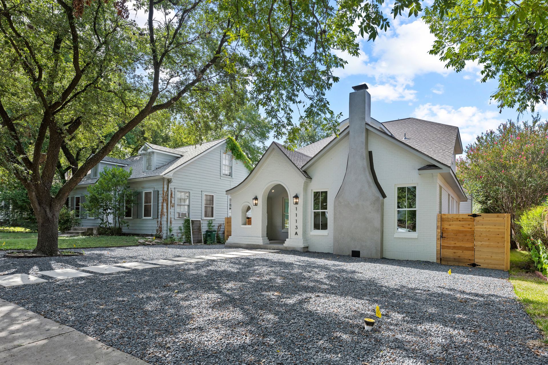 A white house with a gravel driveway in front of it.