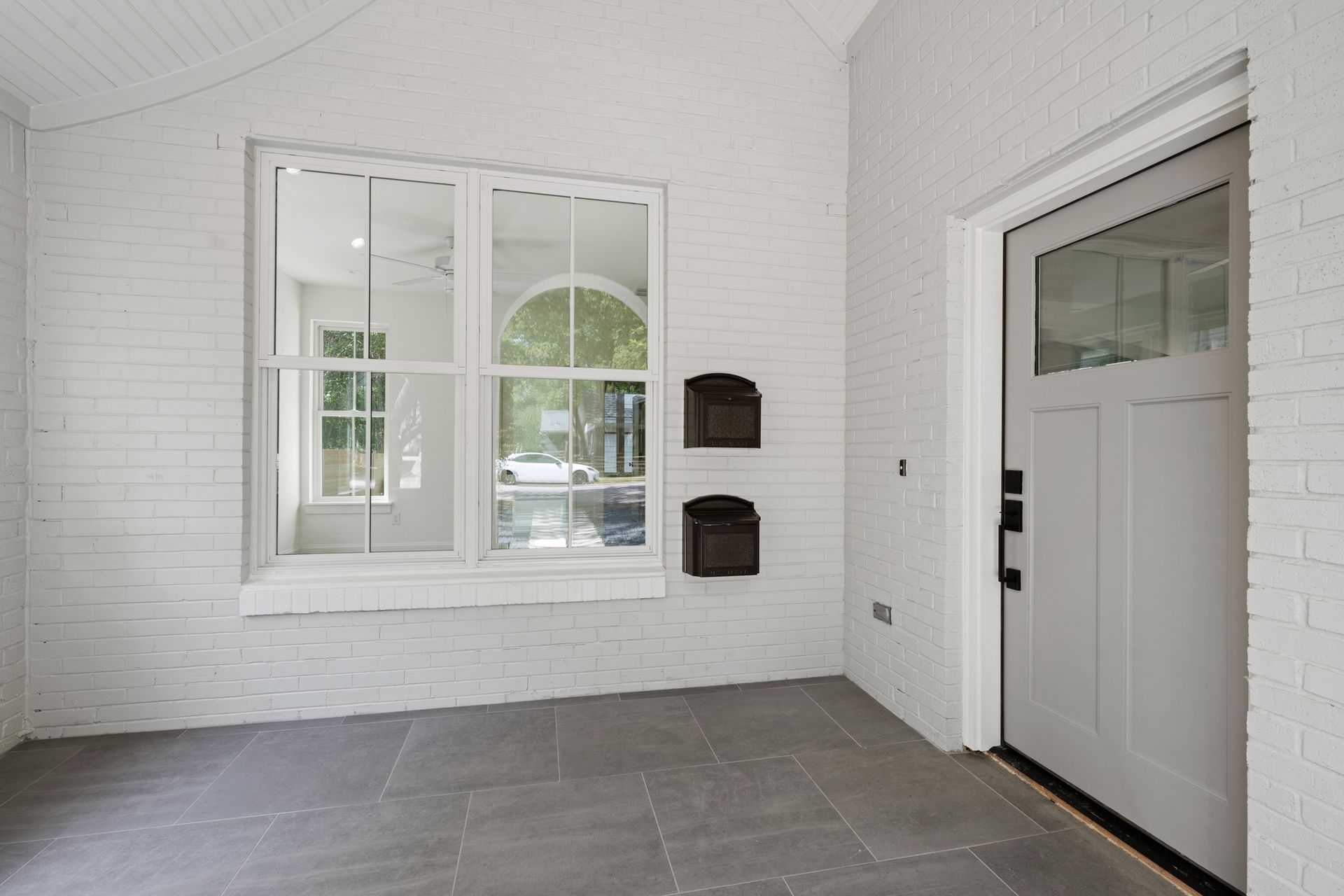 An empty room with white brick walls and a white door.