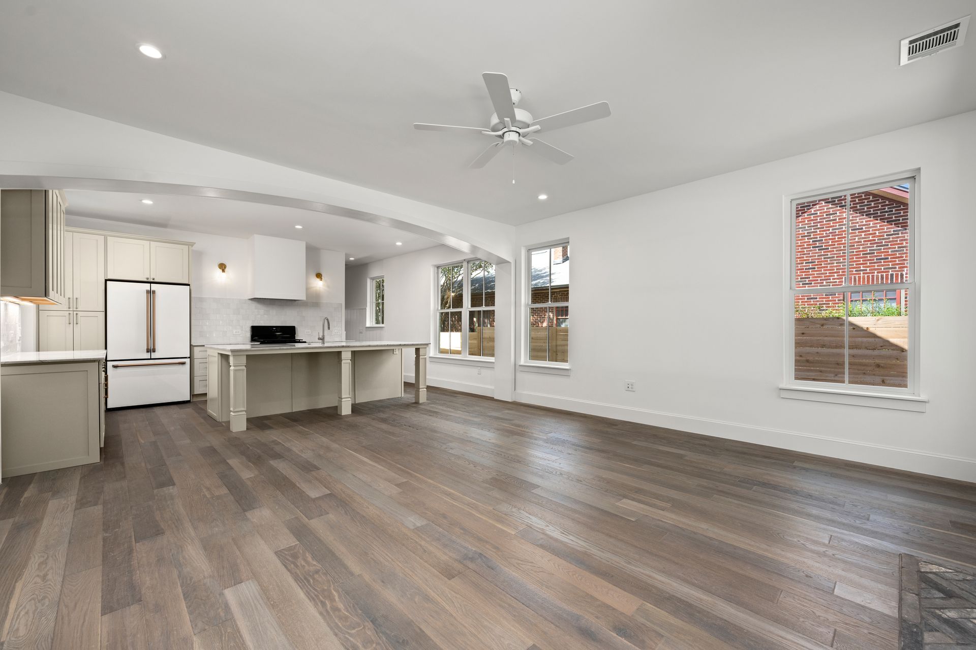 An empty living room with hardwood floors and a ceiling fan.