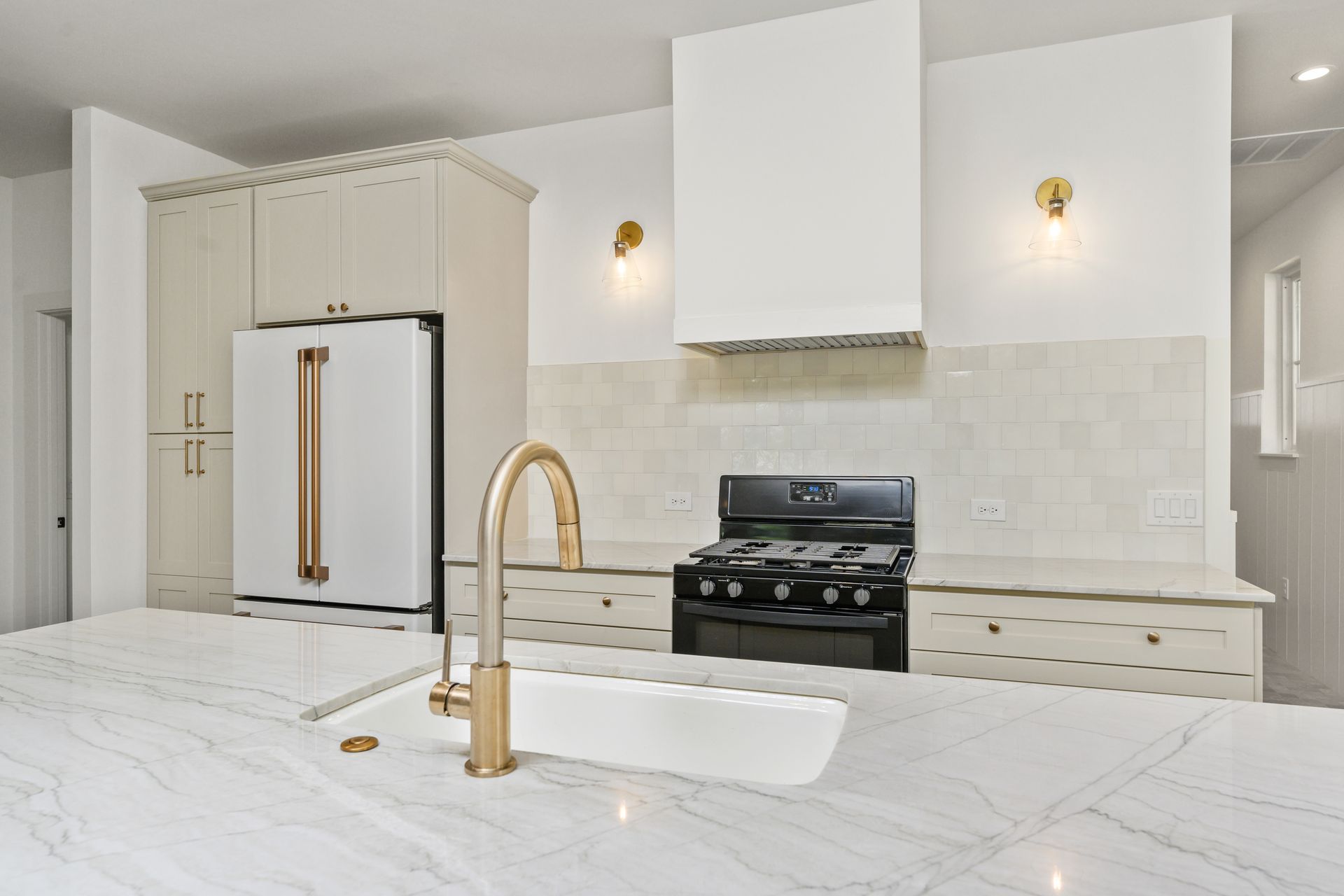A kitchen with white cabinets , a stove , a sink , and a refrigerator.