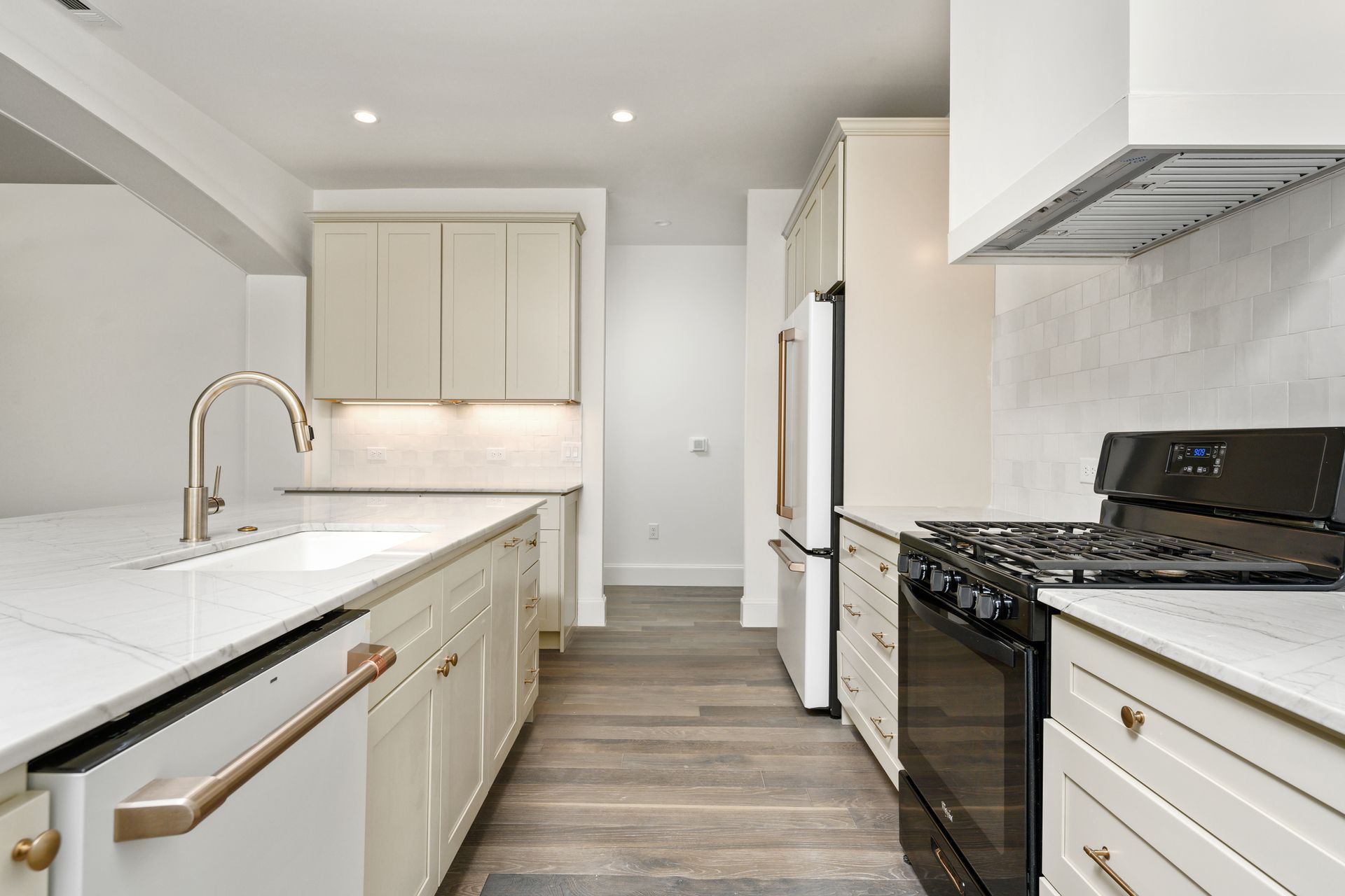 A kitchen with white cabinets , black appliances , a sink , and a stove.