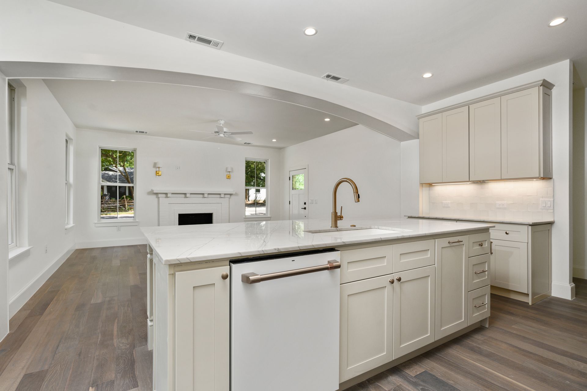 A kitchen with white cabinets , a large island , a sink , and a dishwasher.