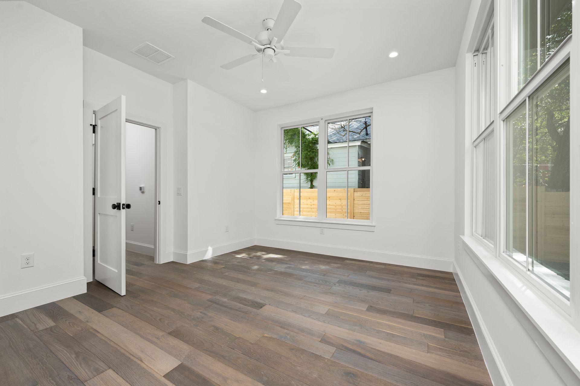 An empty room with hardwood floors and a ceiling fan.