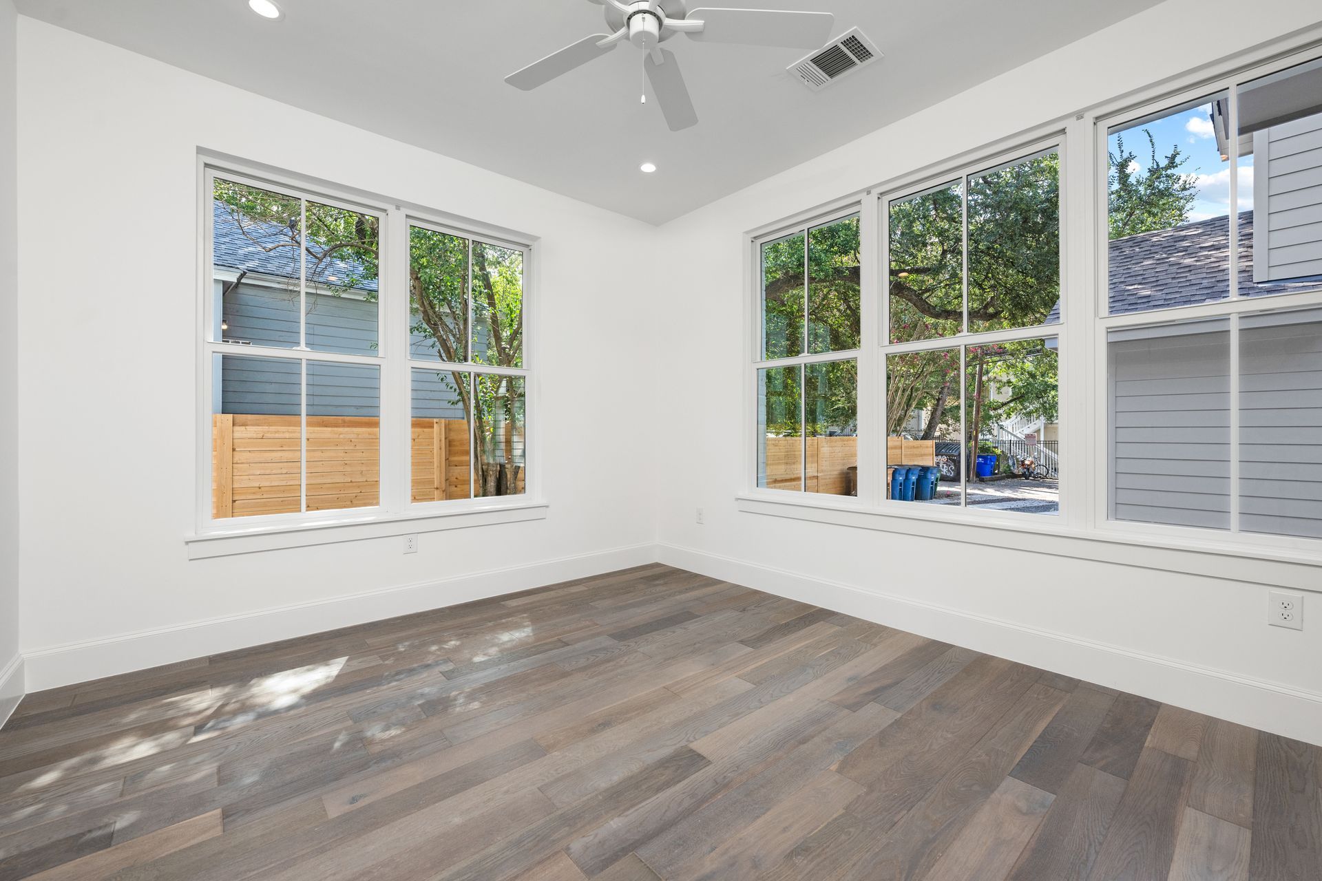 An empty room with a ceiling fan and lots of windows.