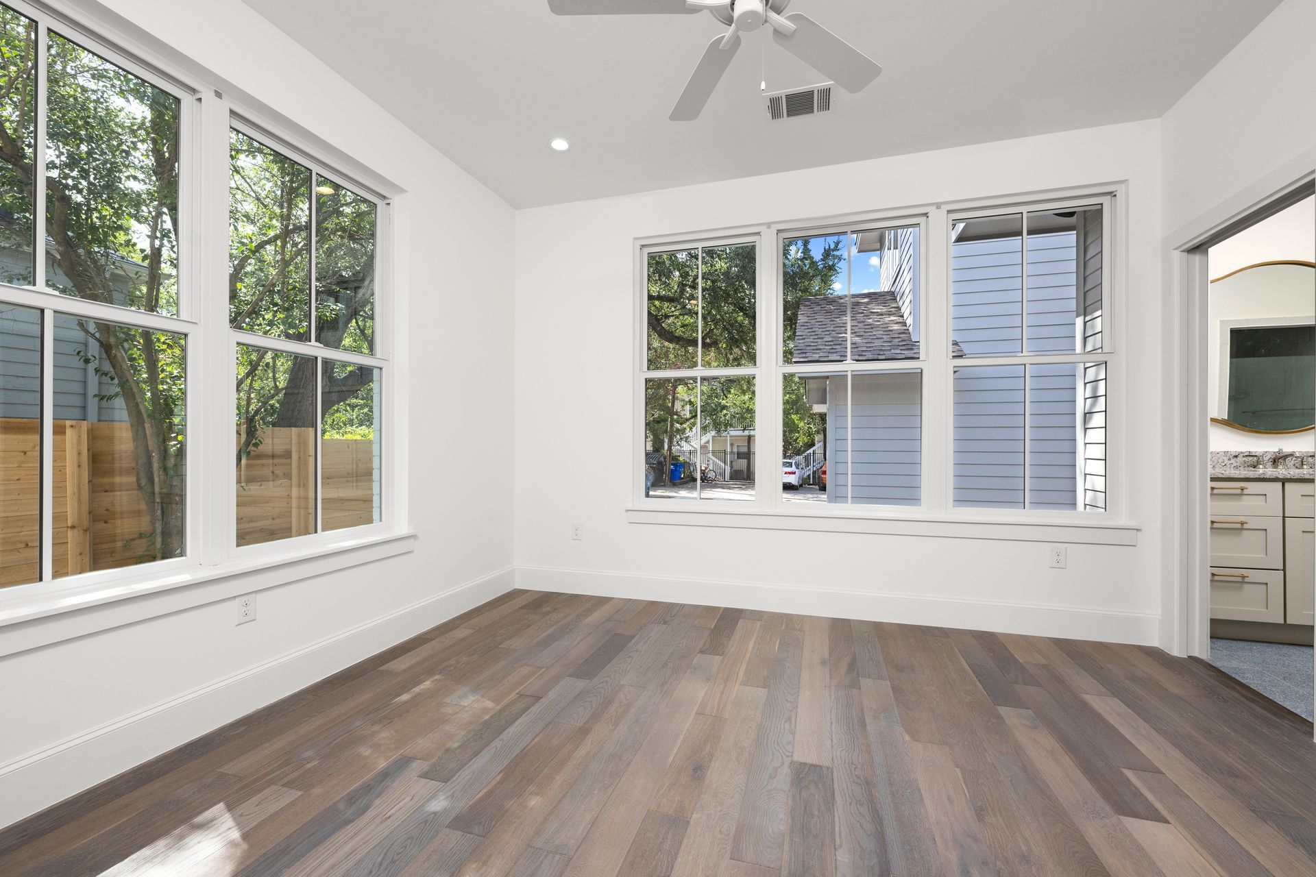 An empty living room with hardwood floors and a ceiling fan